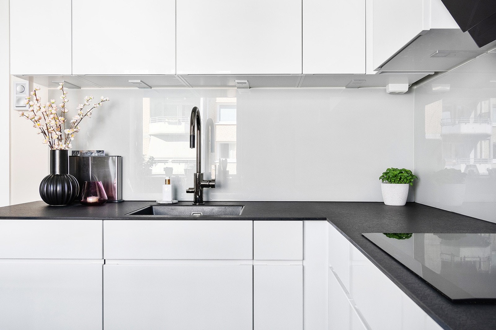 Moderne kjøkken fra 2020 med med laminert benkeplate og lekkert montert glassplate mellom benkeplate og overskap. Kjøkkenet er godt utstyrt med stikkontakter og justerbar belysning over benkeplate Galleribilde