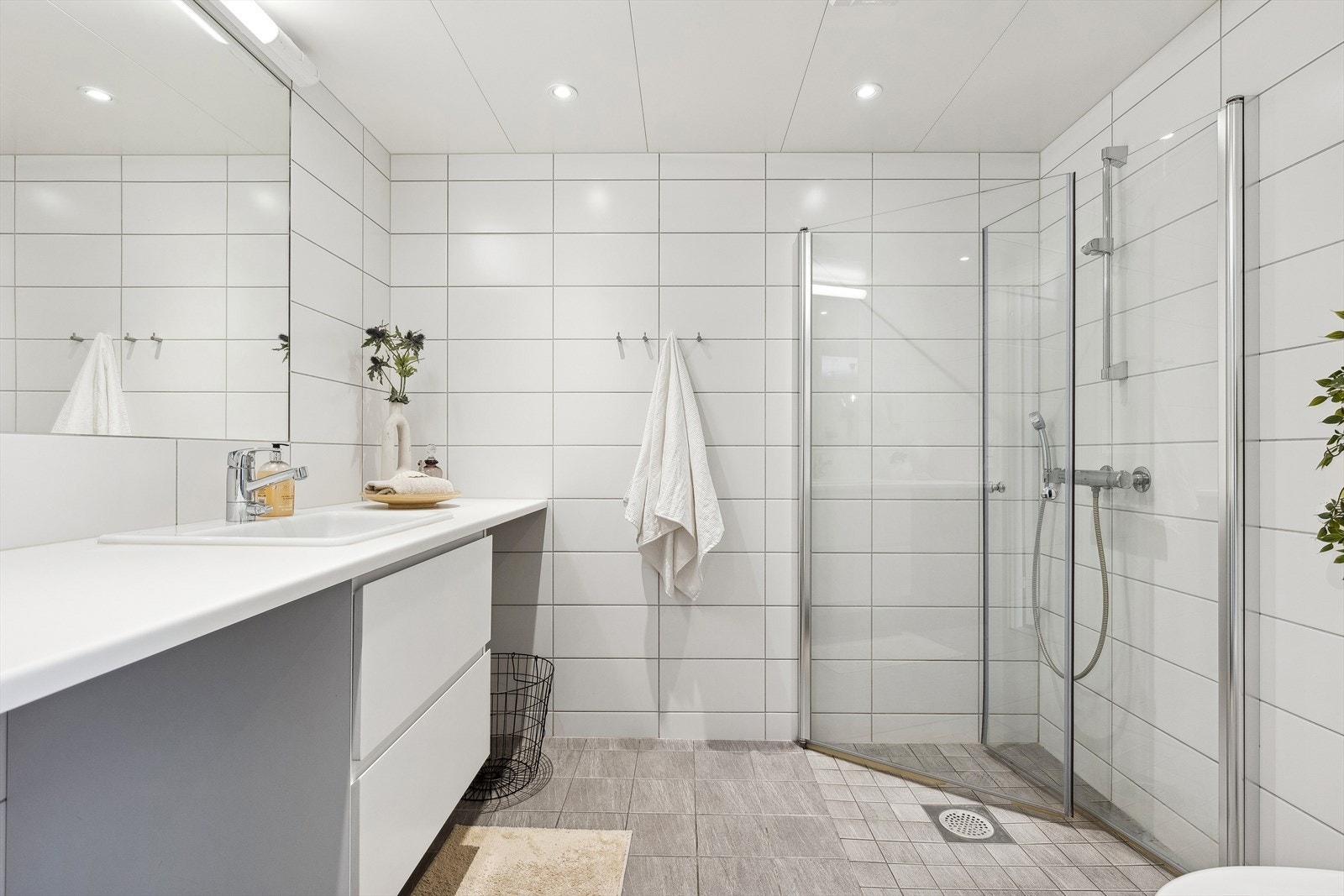 Moderne bad med tidløse fliser på både gulv og vegger. Belysningen er integrert i taket og kan dimmes. Gulvet har varmekabler, toalettet er vegghengt, og dusjdørene i glass kan svinges inn. Galleribilde