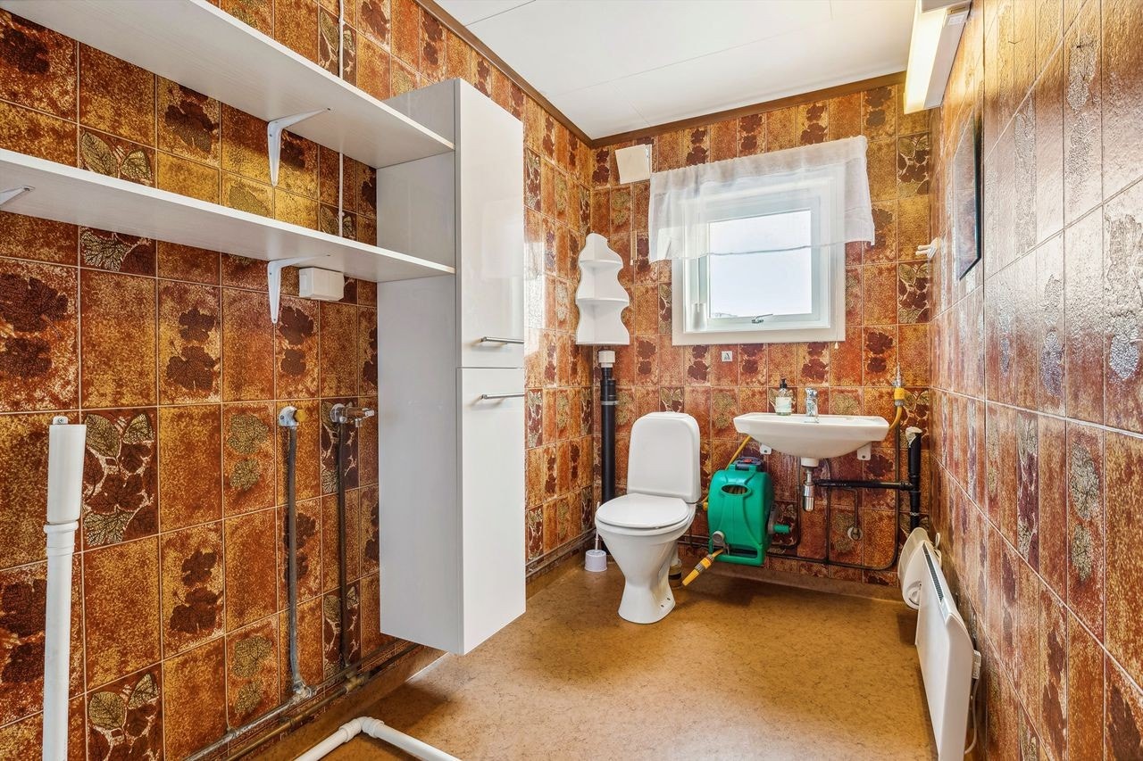 Enkelt bad fra ca 1980, med belegg på gulv og våtromstapet på vegger. Galleribilde