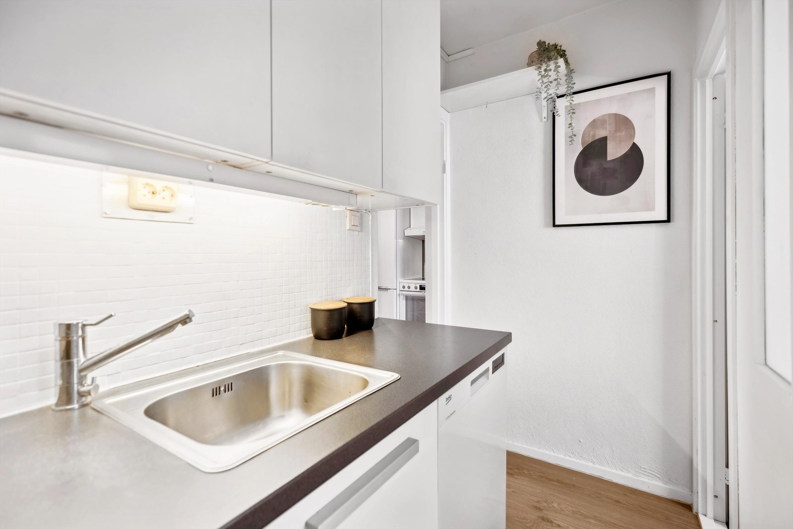 Laminat benkeplate med nedfelt kum i rustfritt stål. Fliser på vegg under overskap. Galleribilde