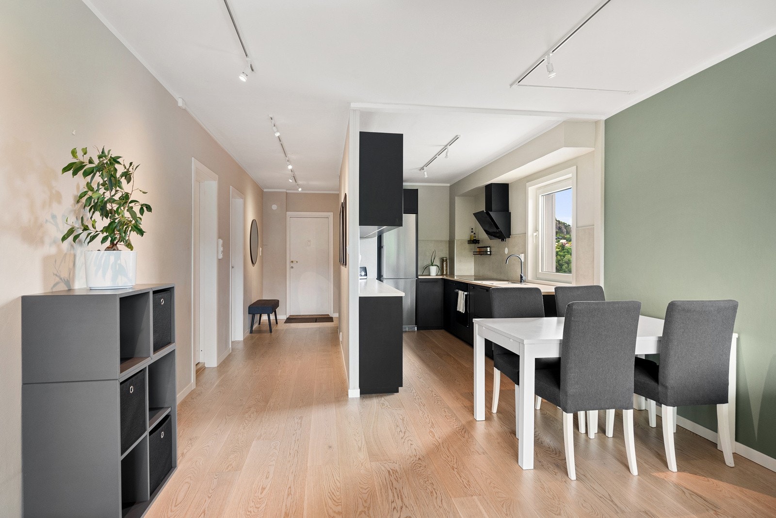 Åpen stue/kjøkkenløsning med parkett på gulvet, malt platekledning/betong på vegger og i himling Galleribilde