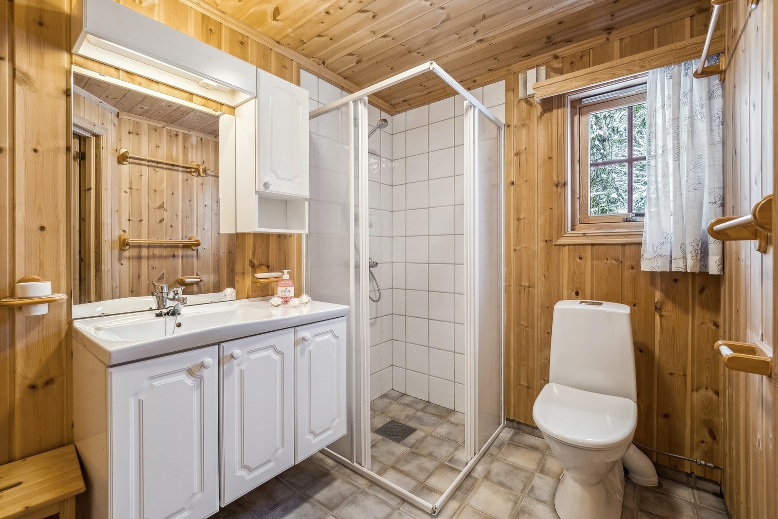 Bad med flislagt dusjhjørne. Badet er innredet med gulvmontert toalett og baderomsinnredning. Galleribilde