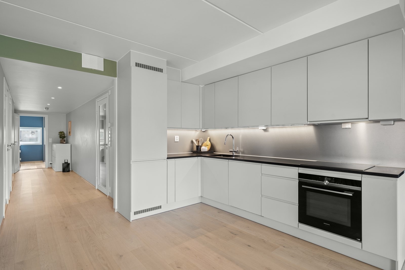 Kjøkkeninnredning er med glatte fronter og benkeplate av stein. Her er det vannavisende plater på veggen over benkeplaten. Galleribilde