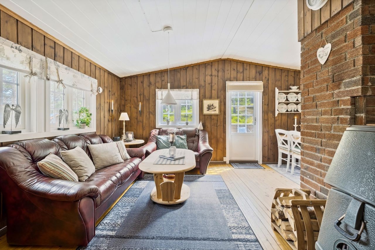 Stuen har brunmalt panel på veggene og lakkert furugulv på gulvet. Stuen er romslig med flere vinduer som slipper dagslyset inn i rommet. Galleribilde