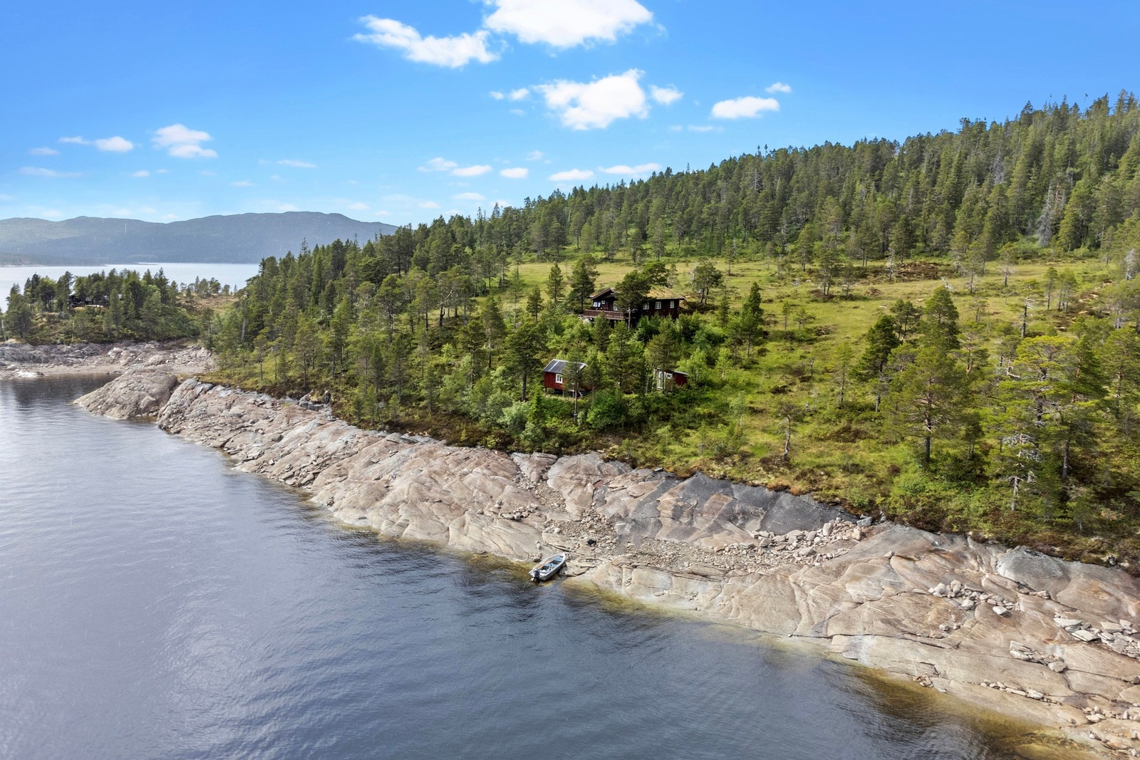 Naust i rekke ved parkering og båt med motor inkludert. Galleribilde