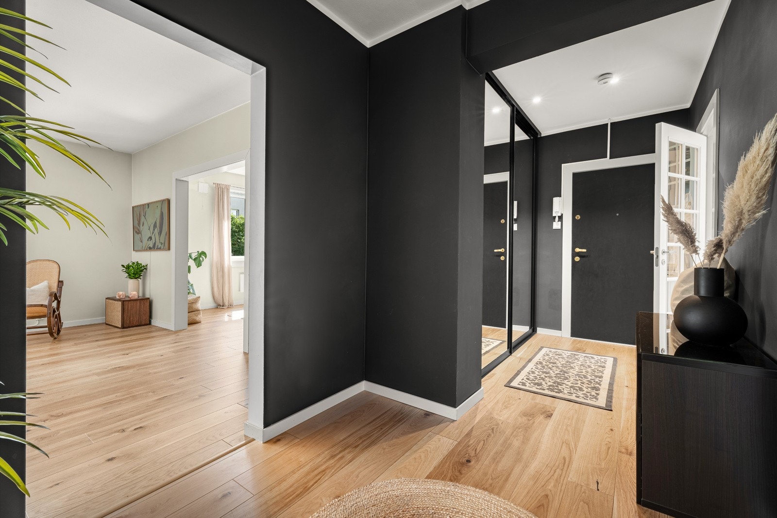Entreen har mørke veggflater, downlights i himling, listefrie åpninger og dør med glassfelt inn til kjøkkenet Galleribilde