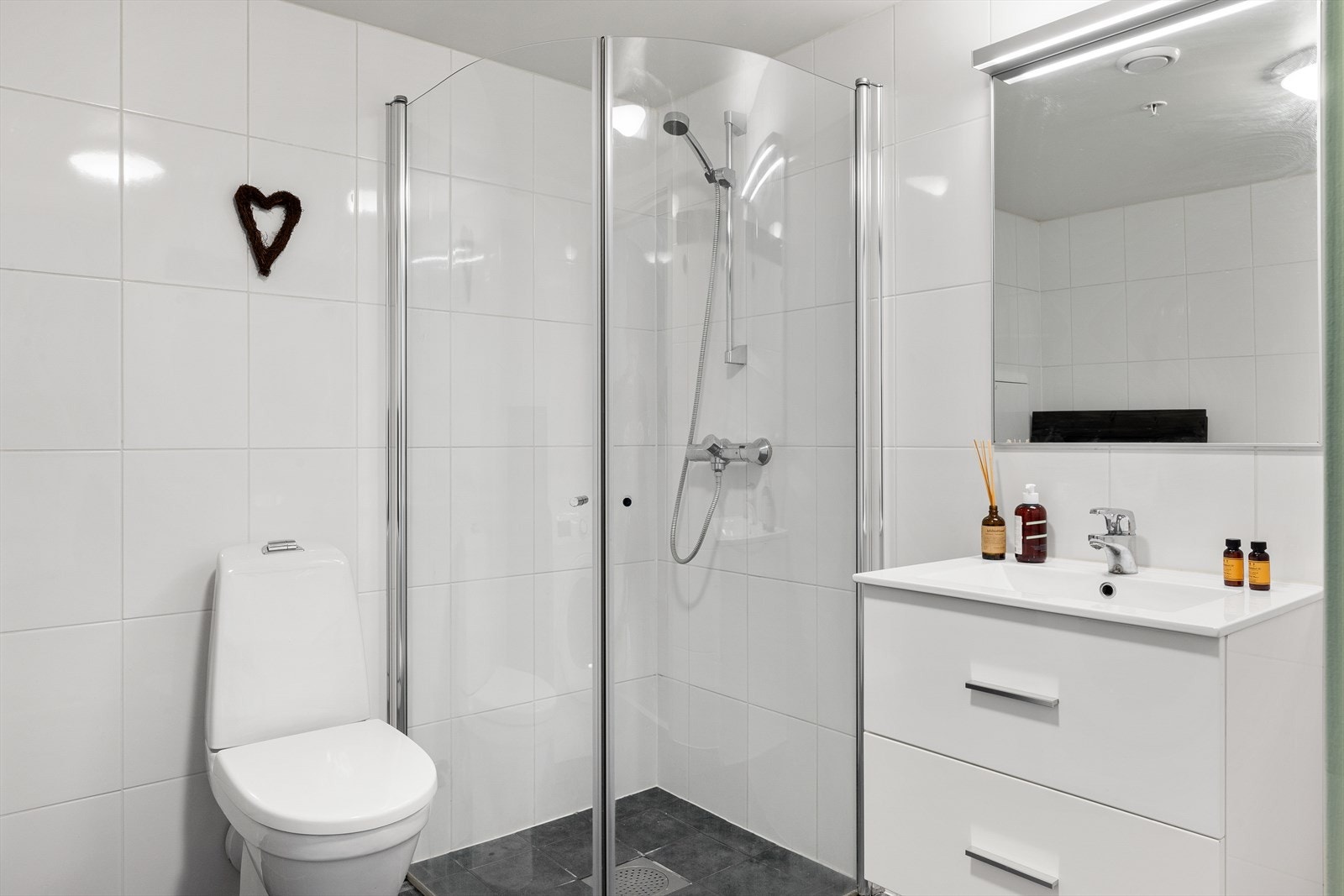 Flott bad med dusjhjørne, wc, servant og opplegg for vaskemaskin. Galleribilde