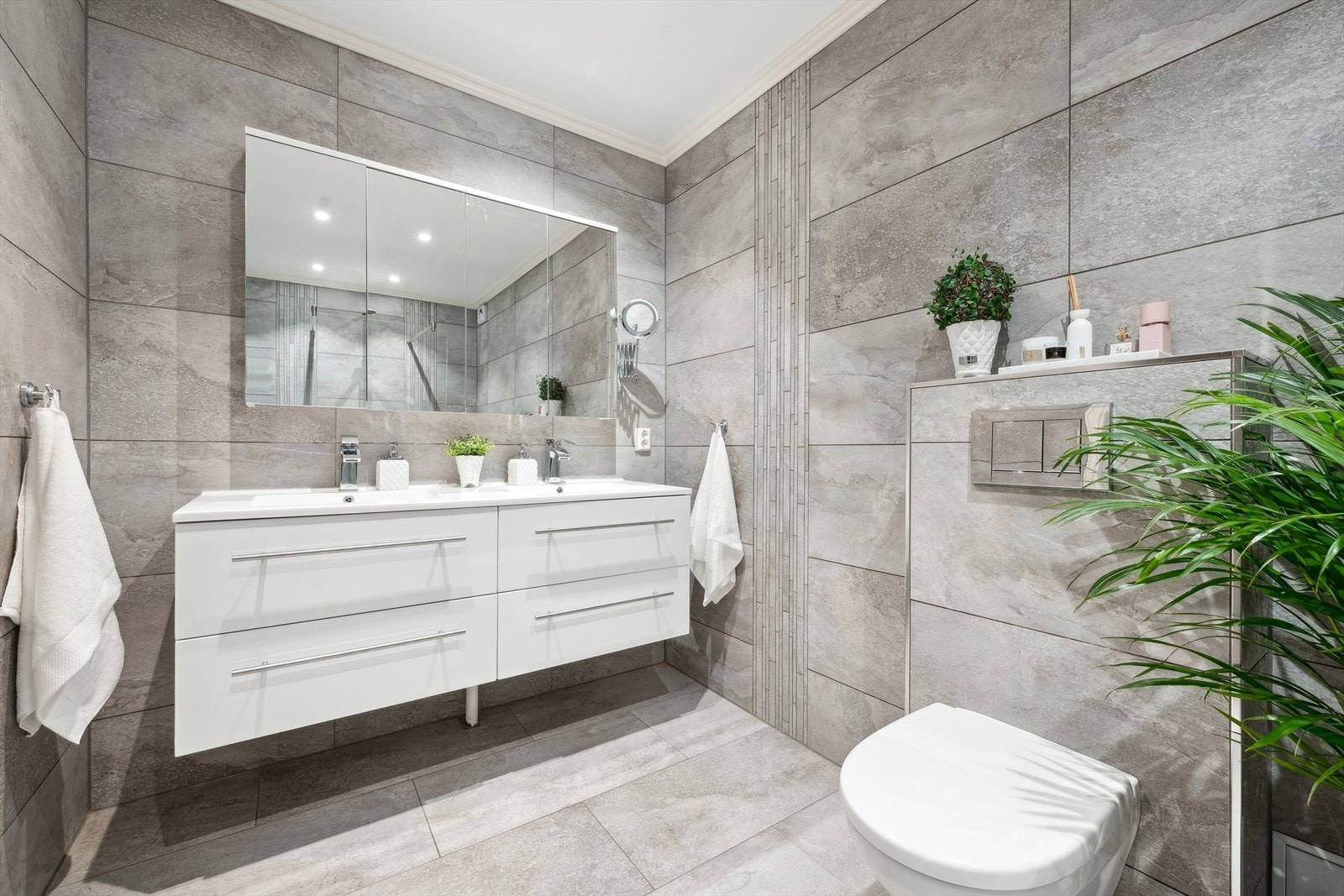 Baderom i 1. etasje fra 2016 med fliser på gulv og vegger i samme gråtone. Badet er utstyrt med dusjhjørne med en stk fastmontert glassvegg og 2- greps blandebatteri. Galleribilde