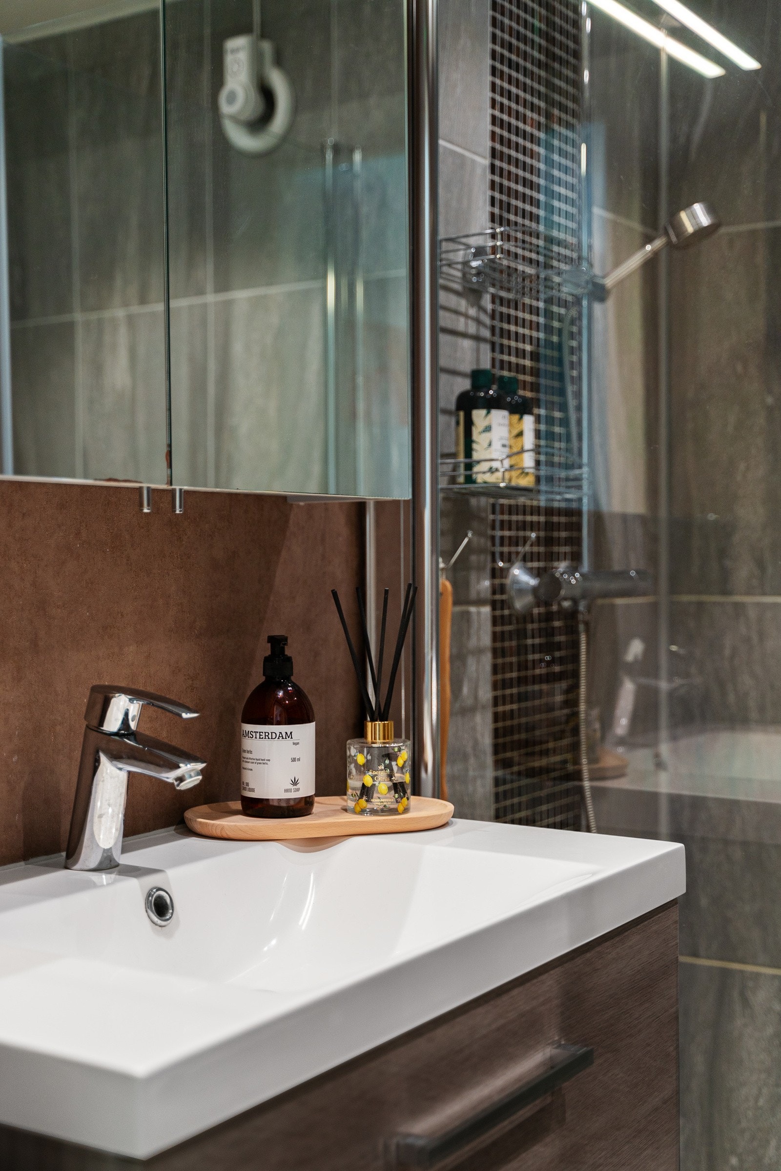 Flislagt bad med gulvvarme, dusjhjørne, pen servantinnredning og vannrør av typen rør-i-rør. Galleribilde