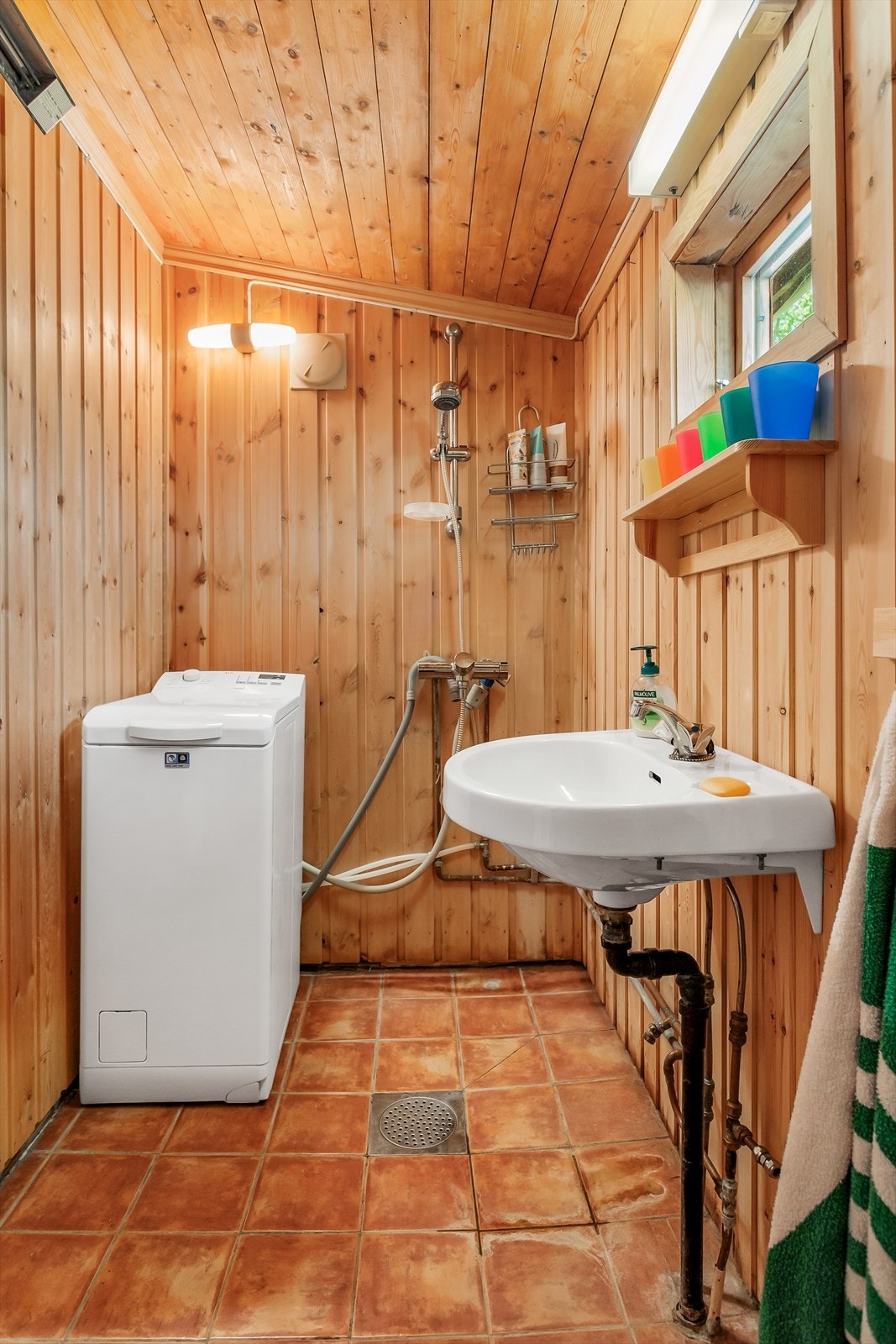 Badet har flislagt gulv med sluk og vegger i treverk. Galleribilde