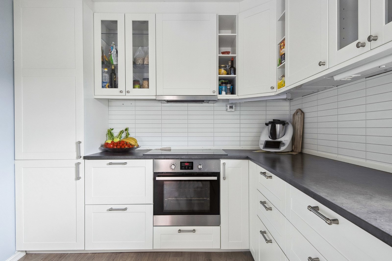 Kjøkkenet har hvite profilerte fronter og integrerte hvitevarer Galleribilde