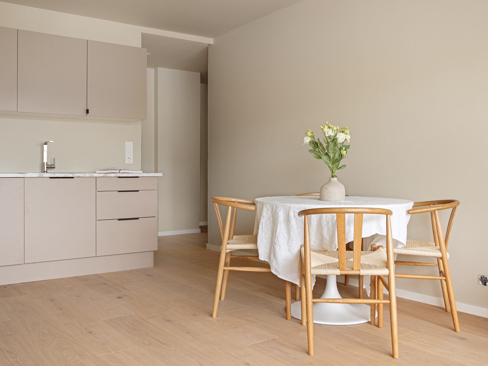 Kjøkkeninnredning med slette fronter og laminat benkeplate. Det er stål oppvaskkum og ventilator. Galleribilde