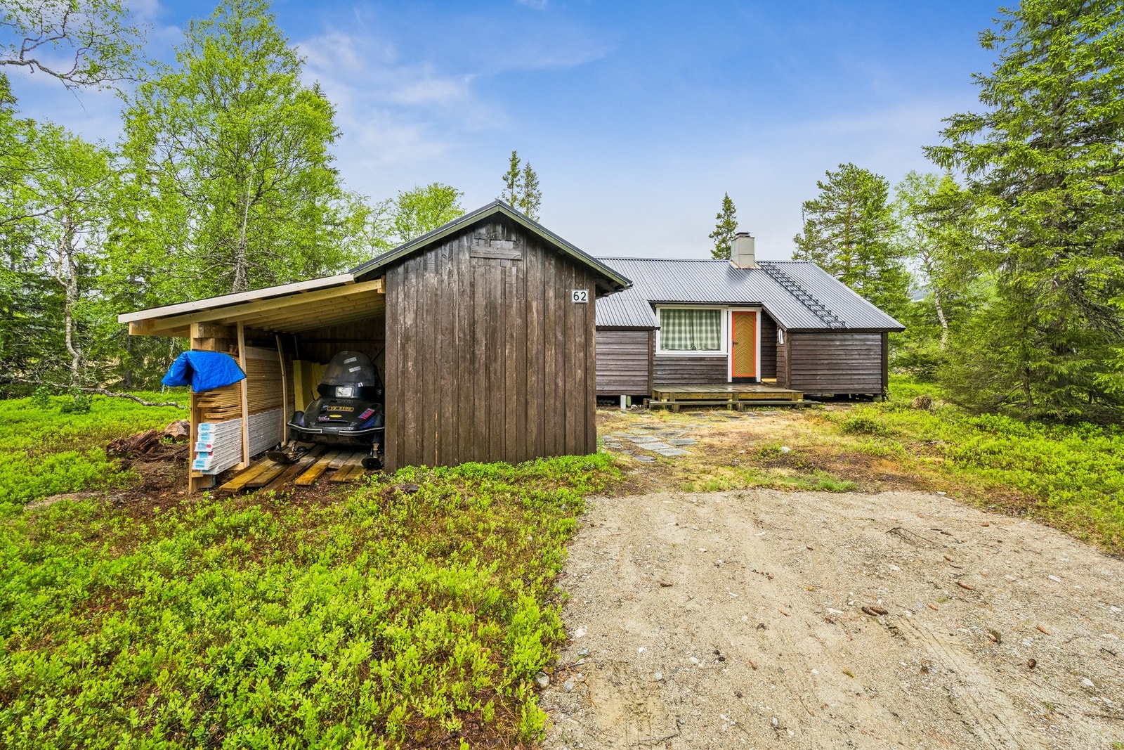 I tillegg til hytta og boden er det et uthus på tomten. Det er også bygd et lite tak for parkering av scooter. Galleribilde