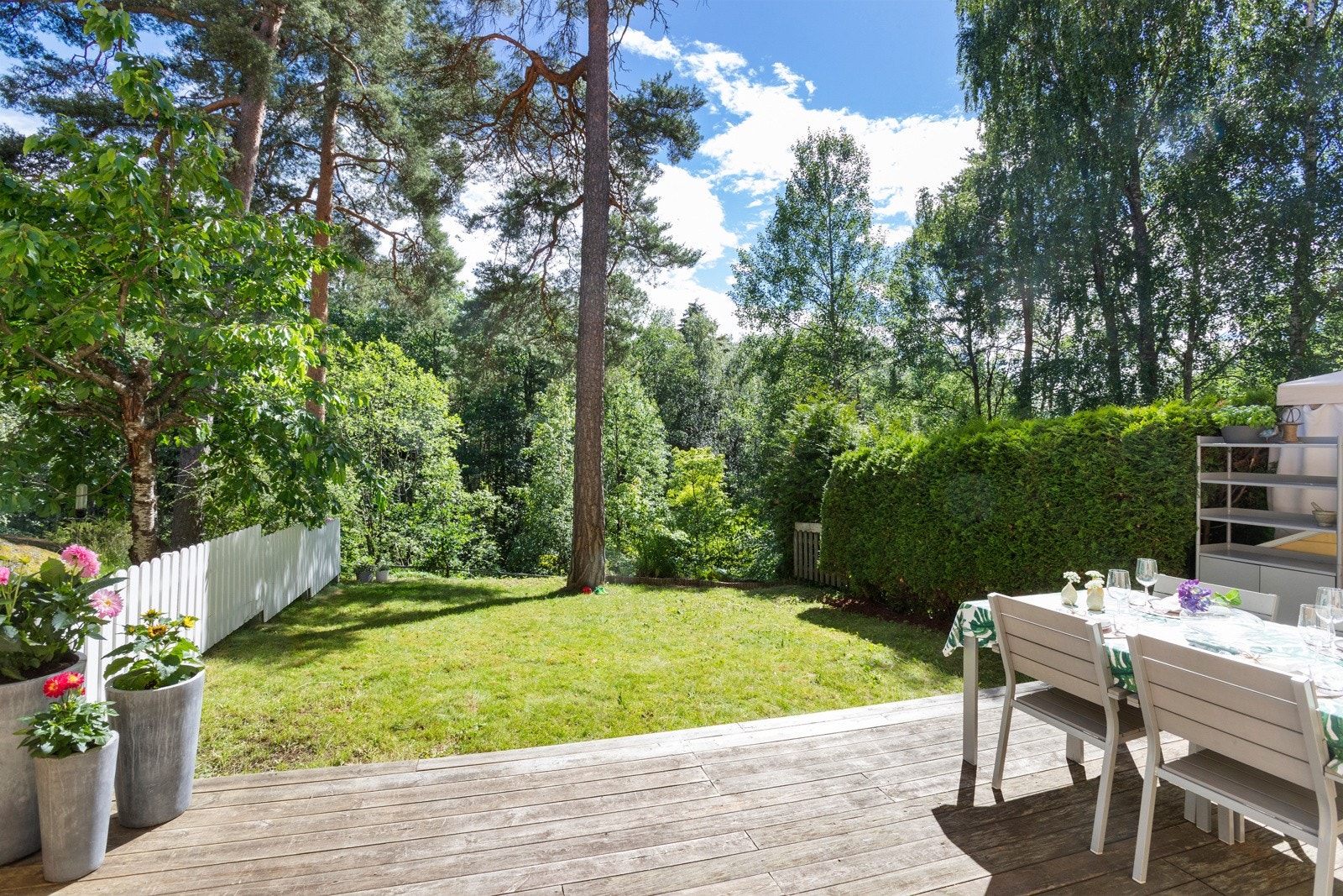 Stuen har utgang til solrik markterrasse pent opparbeidet med platting og plen Galleribilde