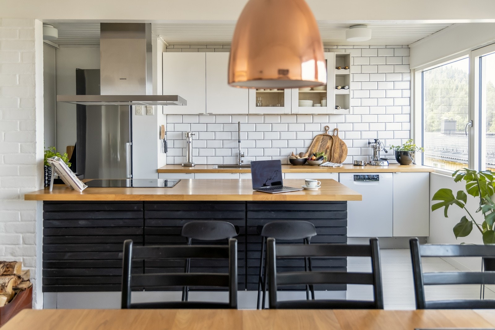 Kjøkkenet har en hvit stilren innredning med mørke spilefronter mot spisestue. Galleribilde