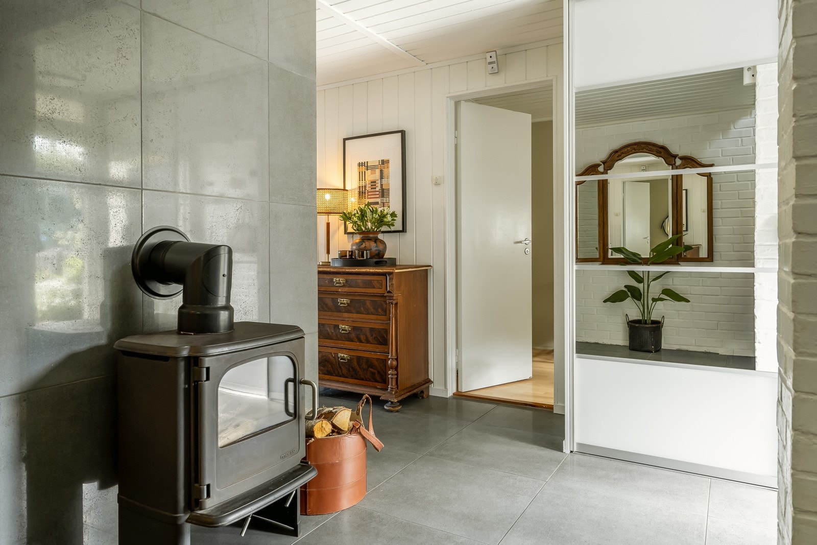 Hallen er flislagt med 60x60 fliser på gulv og har varmekabler. Her er skyvedørsgarderobe med god oppbevaringsplass. Vedovn både her og på stuen i 2.etasje. Galleribilde