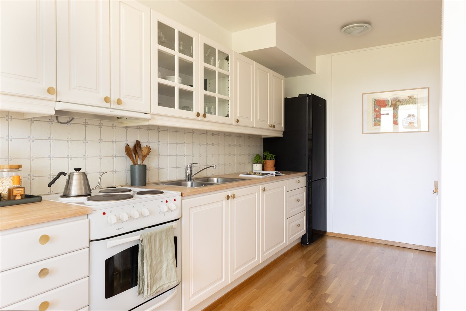 Fliser over kjøkkenbenk og benkebelysning under overskap. Kjøkkenventilator med kullfilter Galleribilde