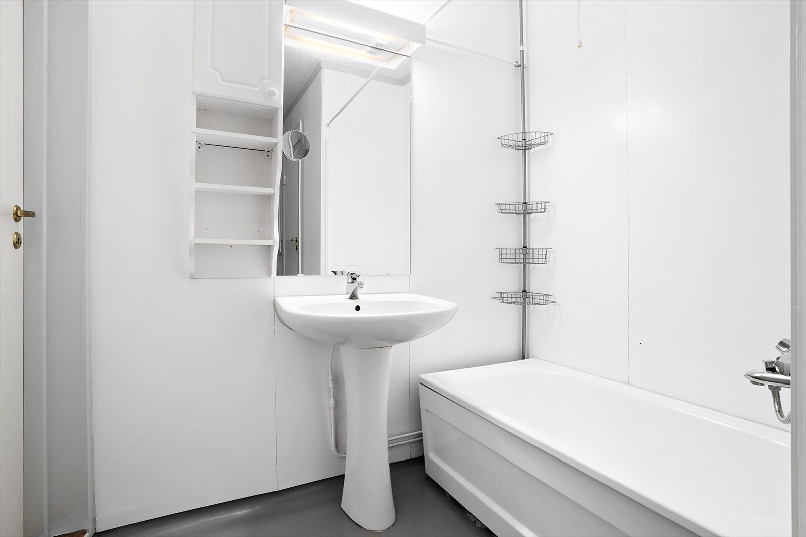 Bad utstyrt med servant, speil med tilhørende belysning og hylle/skap, vegghengt skap og badekar med dusjopplegg. Galleribilde