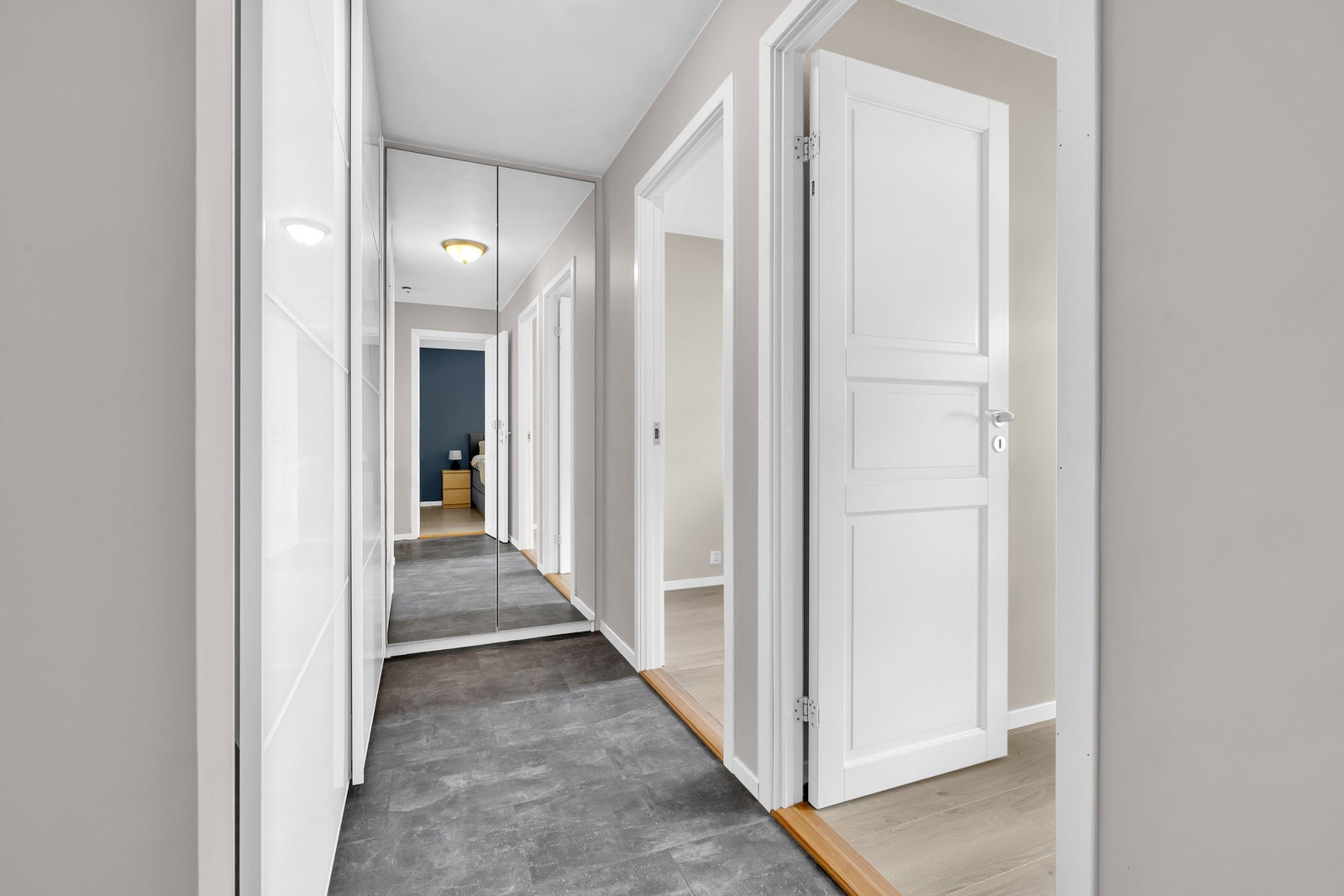 Gang med gode oppbevaringsmuligheter i skyvedørsgarderobe, og speilskap i enden. Galleribilde