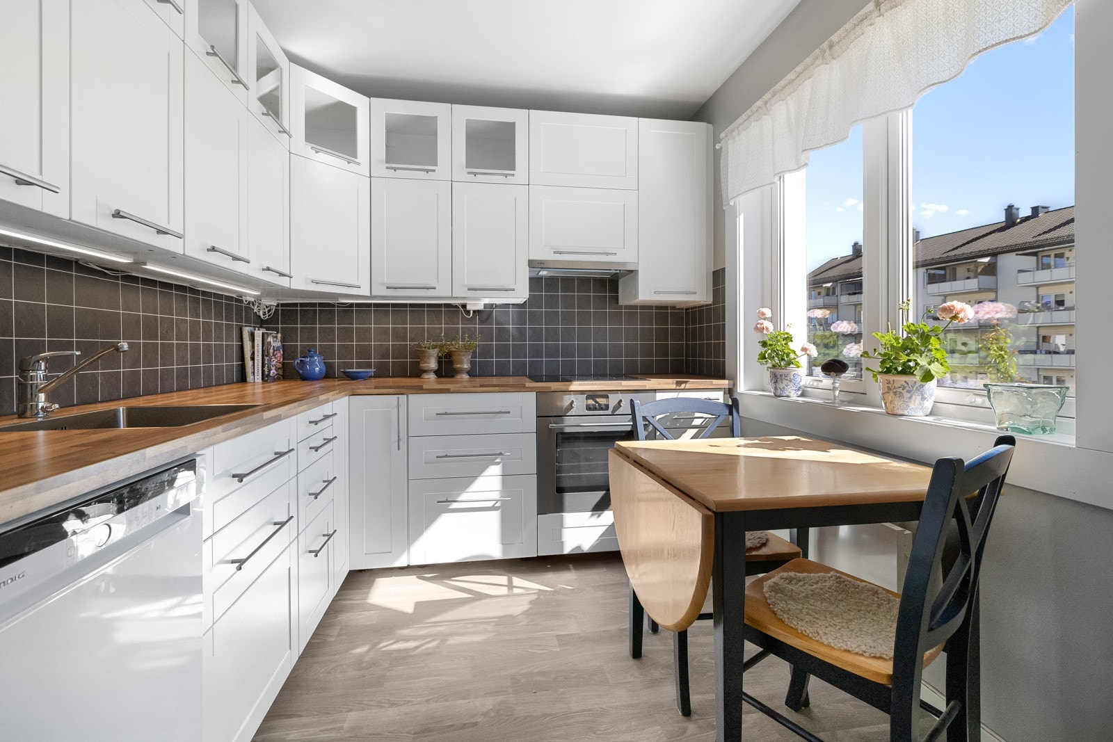 Kjøkken i separat løsning med laminat på gulv og god plass til spisebord. Galleribilde