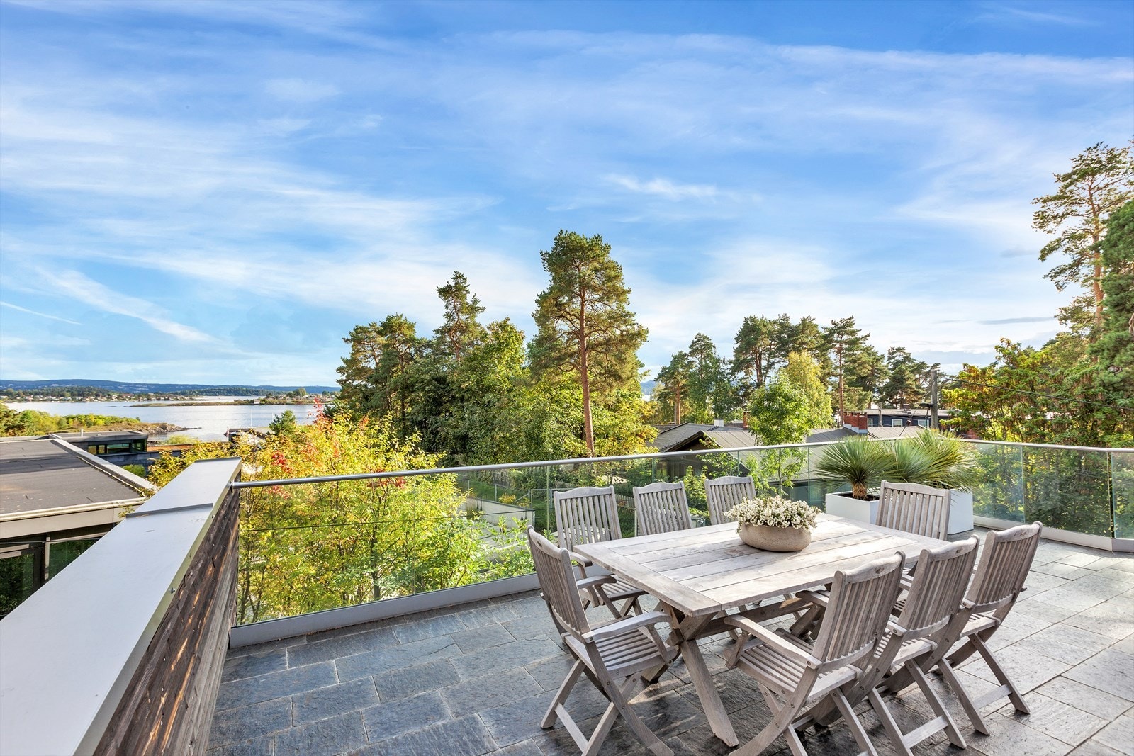 Stor terrasse med skifer på gulvet og rekkverk i glass og rustfritt stål. Galleribilde