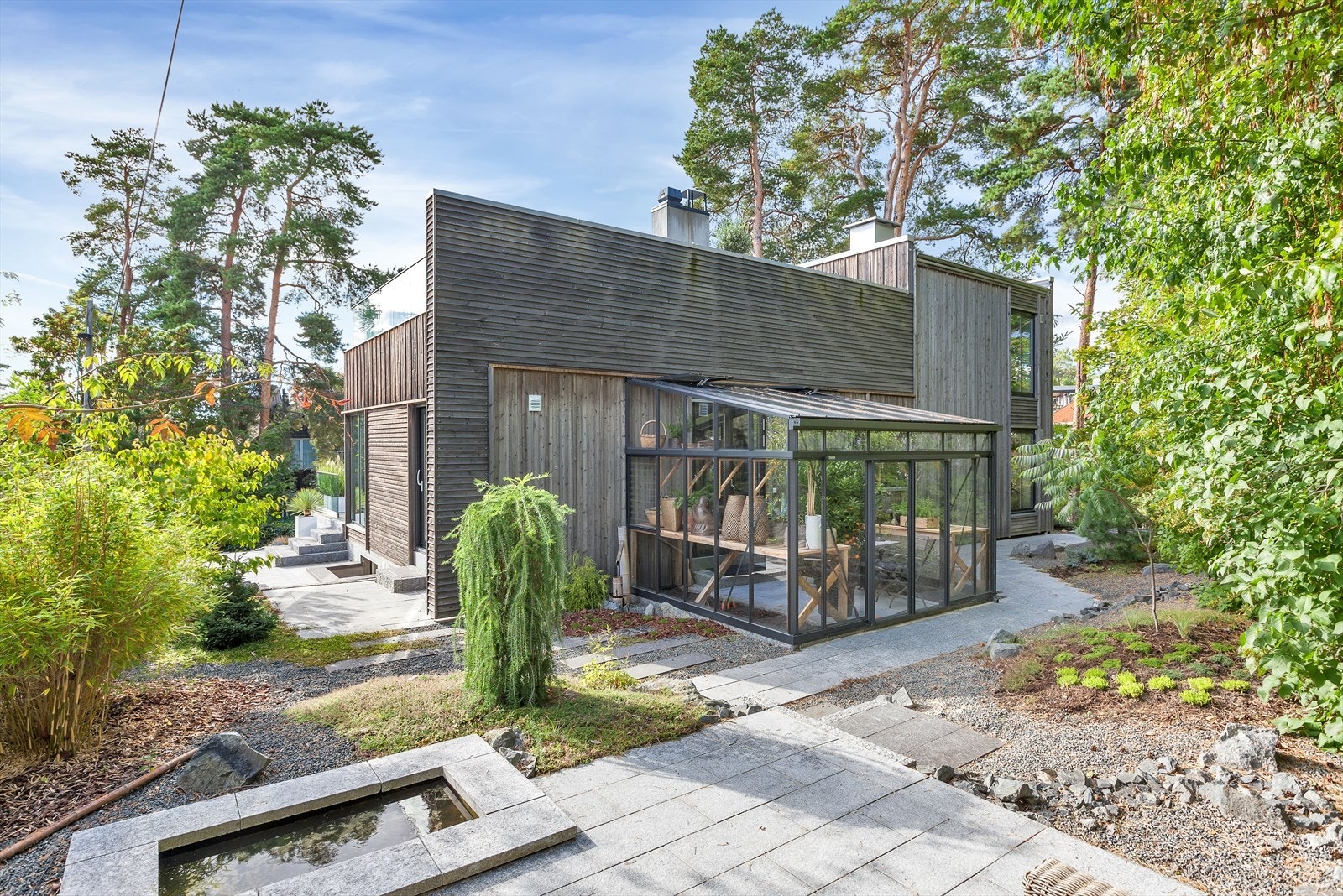 Frodig hage med hellelagte uteplasser og trapper i naturstein. Flott vinterhage med flere bruksmuligheter. Galleribilde