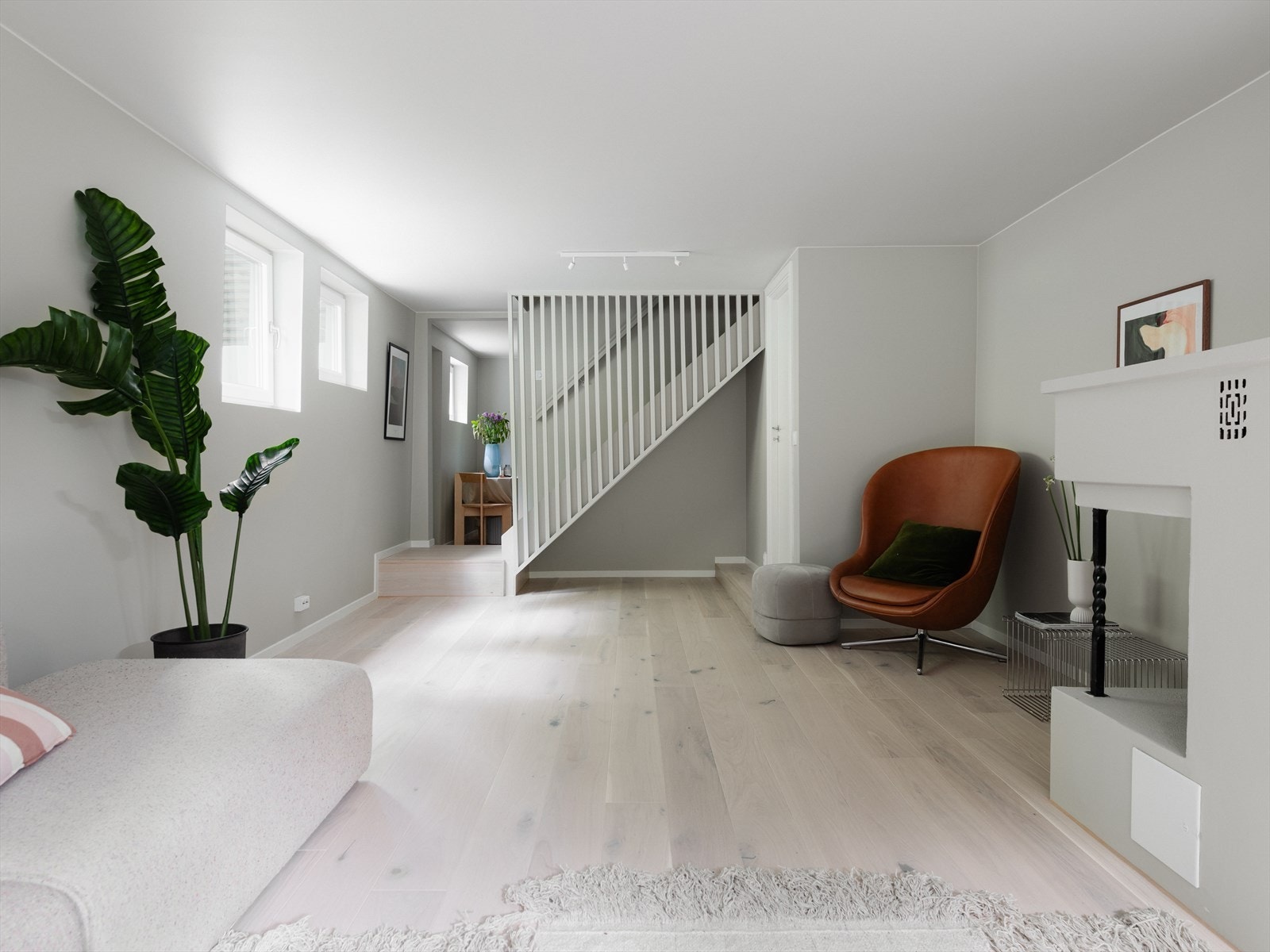 Fra 1.etasje er det trapp ned til kjeller som inneholder en stor peisestue, vaskerom, stue og soverom med eget bad Galleribilde