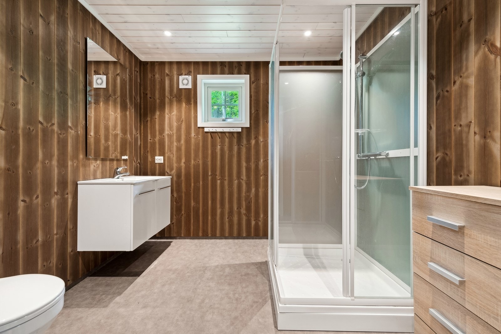 Baderom med servant med underskap, dusjkabinett og gulvmontert wc. Mekanisk avtrekk. Galleribilde