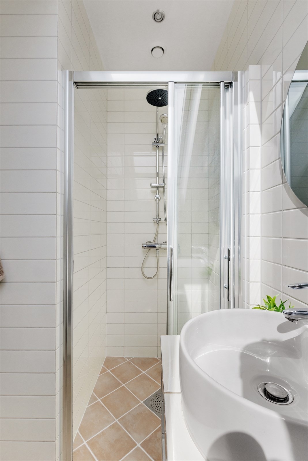 Badet inneholder plassbygd baderomsinnredning med fliser, møbel servant, speil m/lys, veggmontert toalett, dusjhjørne m/glassdør og opplegg for vaskemaskin. Galleribilde