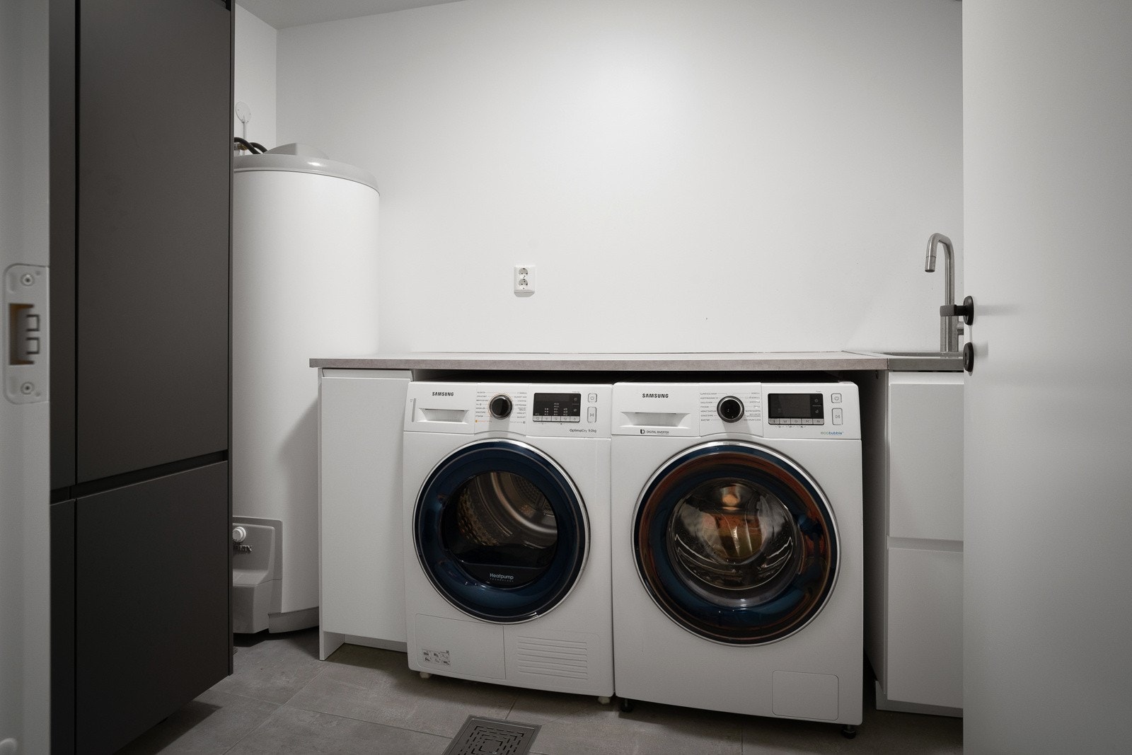 Separat vaskerom fra 2020 med fliser på gulv, varmekabler og opplegg for to vaskemaskiner. Galleribilde