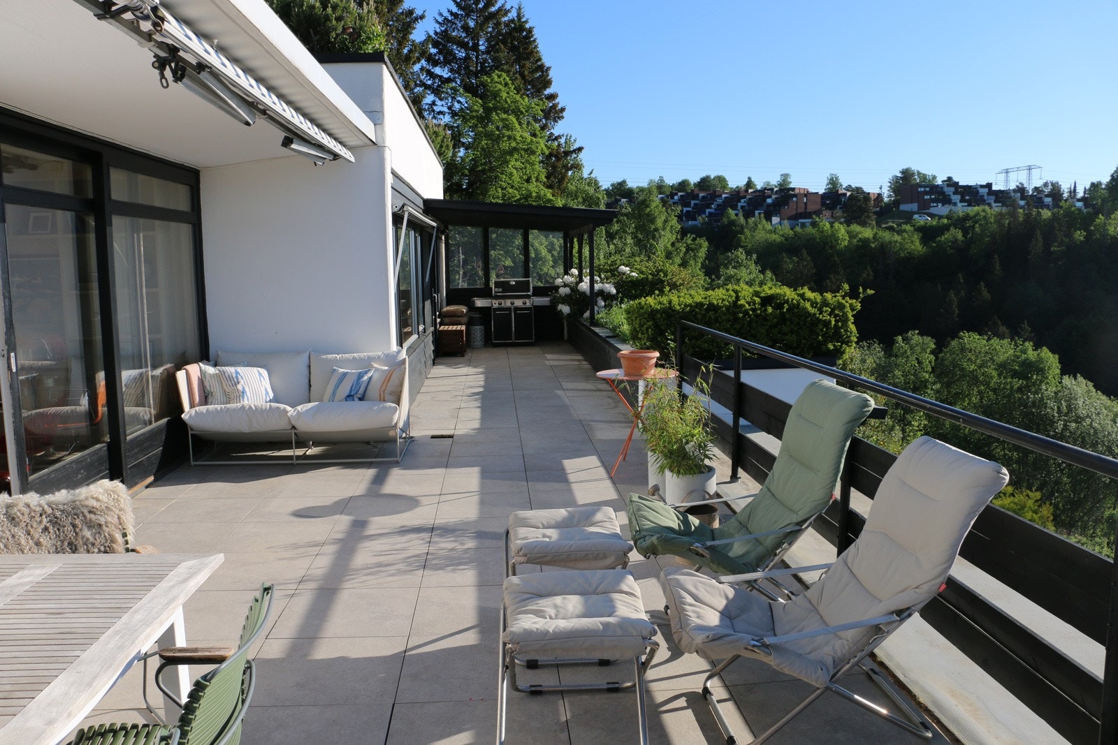 Skjermet terrasse med flislagt gulv, markiser og blomsterkasse. Galleribilde