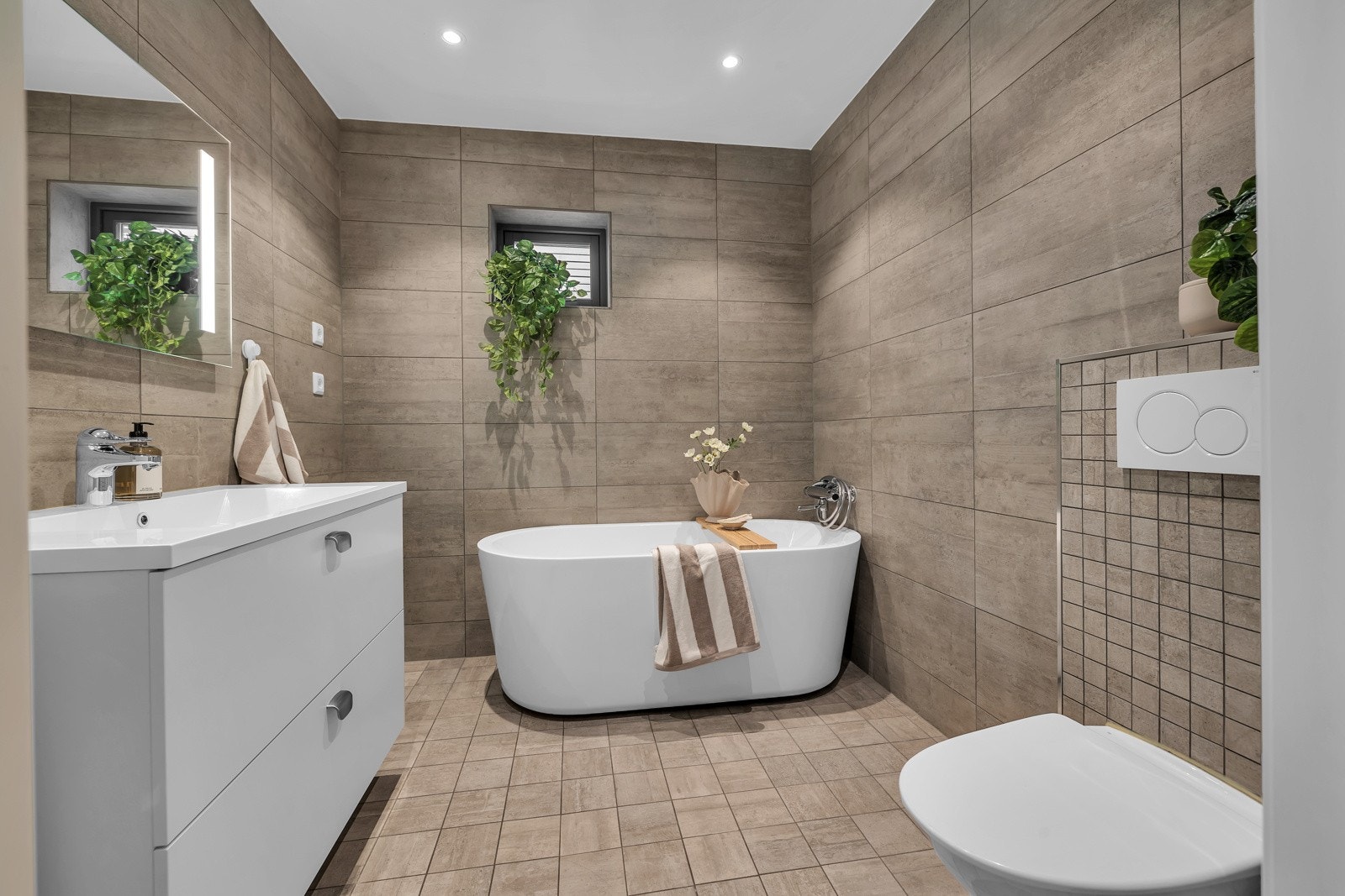 Flott bad på ca. 5,5m2 med fliser på gulv og vegger, badekar, innfelt belysning i tak m.m. Galleribilde