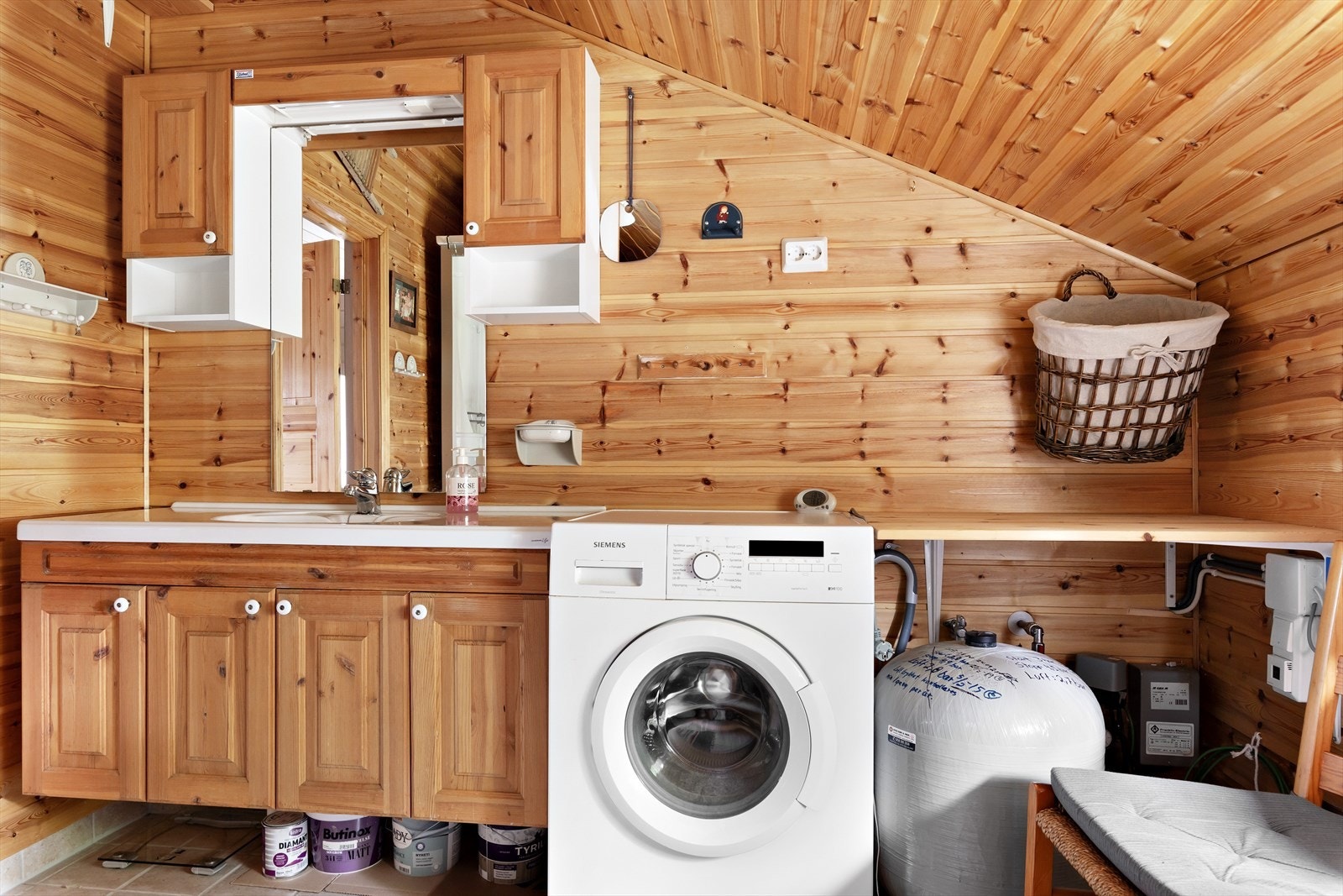 Romslig bad/vaskerom har innredning med nedfelt servant i benkeskap, veggskap og speil, forbrennings toalett, dusjkabinett og opplegg for vaskemaskin. Galleribilde