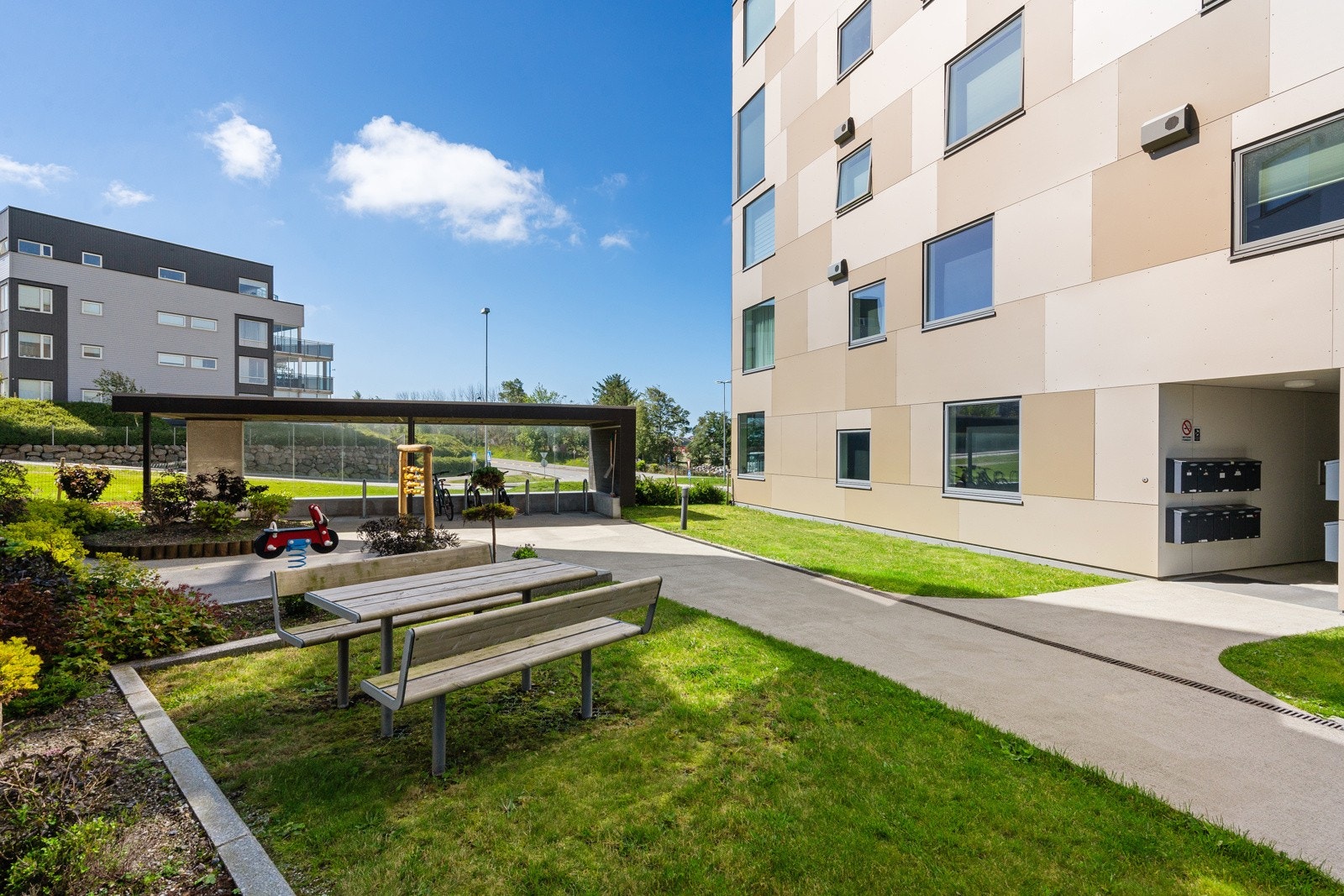Fellestomt opparbeidet med asfaltert vei, plenareal, sittegrupper og diverse beplantninger. Galleribilde