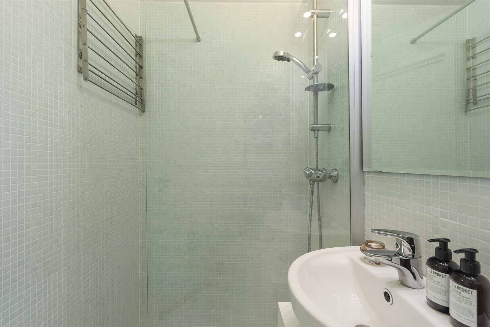 Badet inneholder toalett, helstøpt servant, skap under servant med slette fronter og dusjvegg i klart glass. Galleribilde