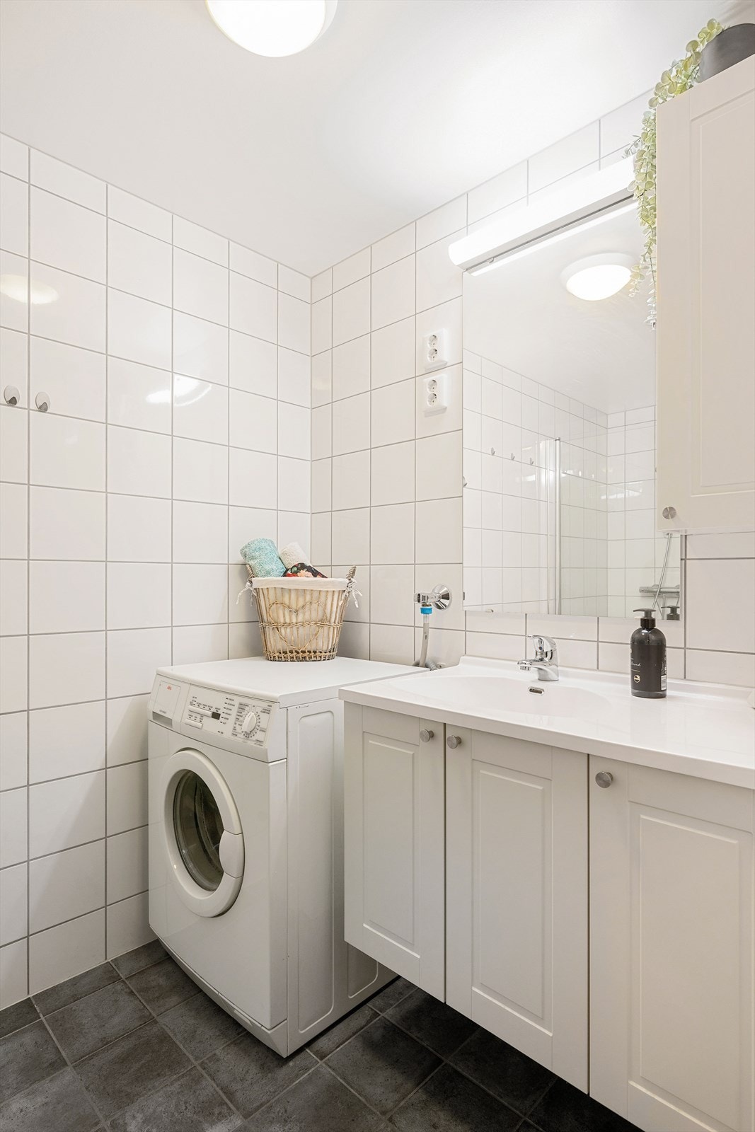 Innredningen består av bred servant, hvitt servantskap, matchende veggskap og speil med lys Galleribilde