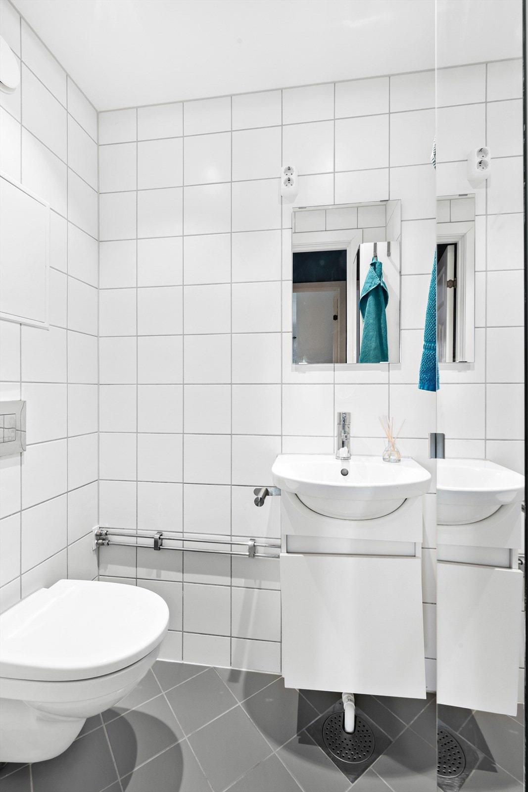 Separat WC rom innredet med veggfestet klosett med innebygget sisterne, med servant og speil på vegg. Galleribilde
