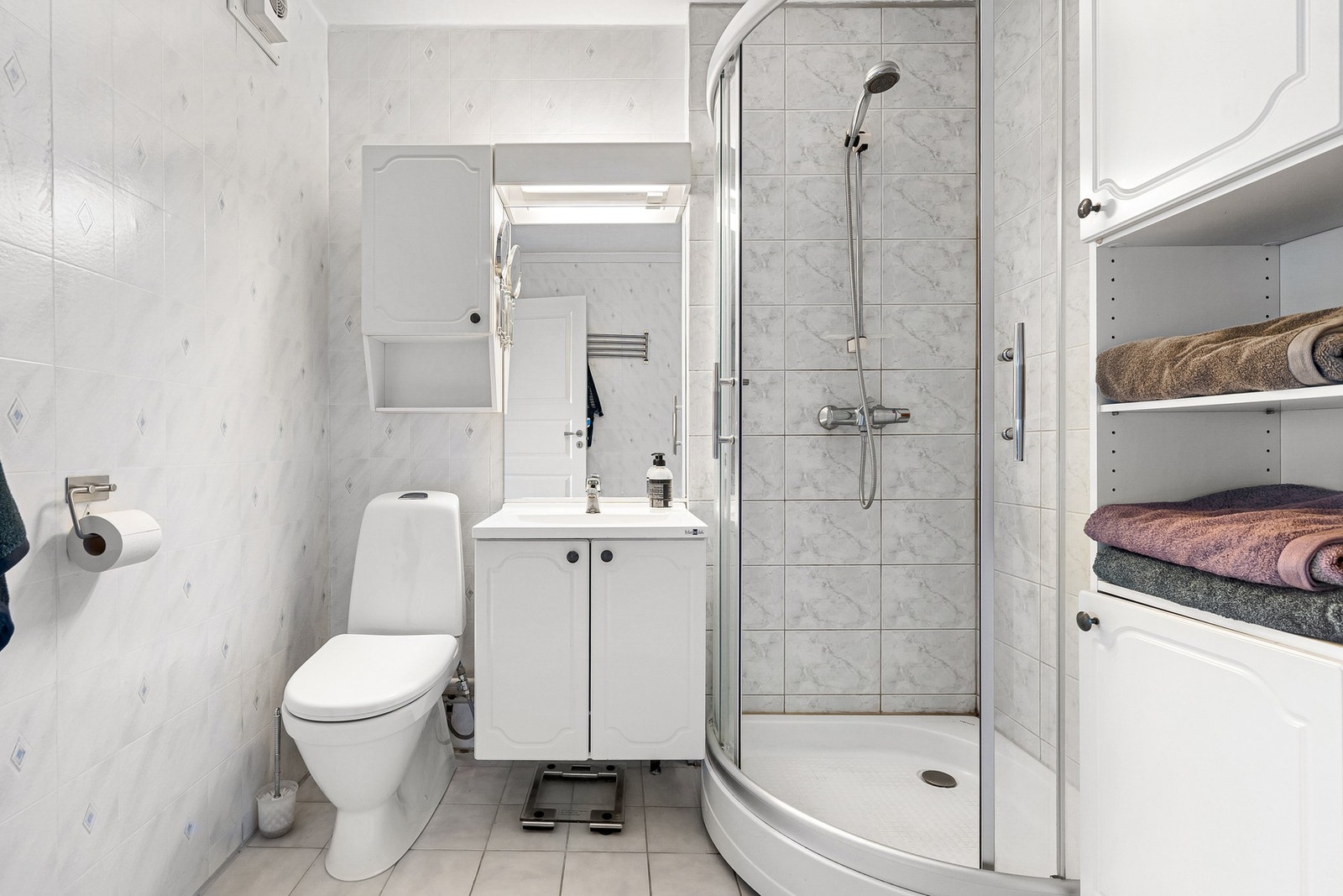 Badet er innredet med dusjkabinett og servant med lys over speil. Galleribilde