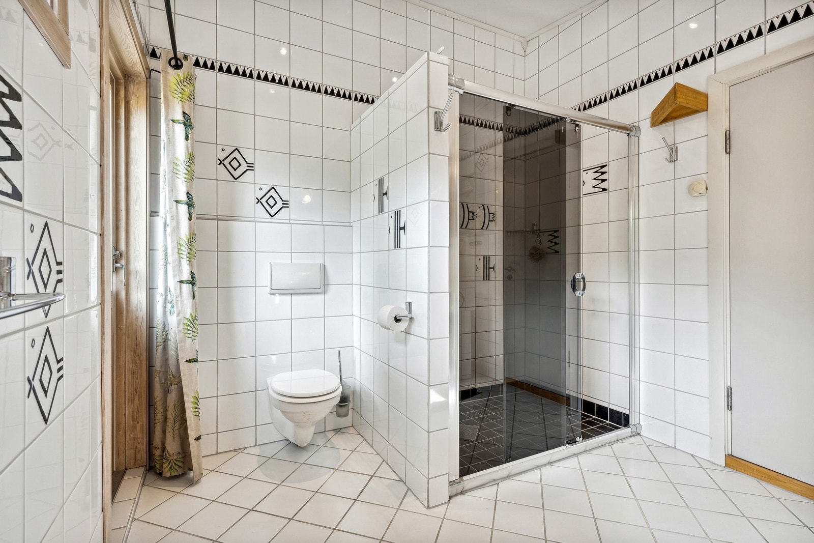 Badet er utstyrt med vegghengt toalett og en stor dusjnisje med skyvedører i glass Galleribilde