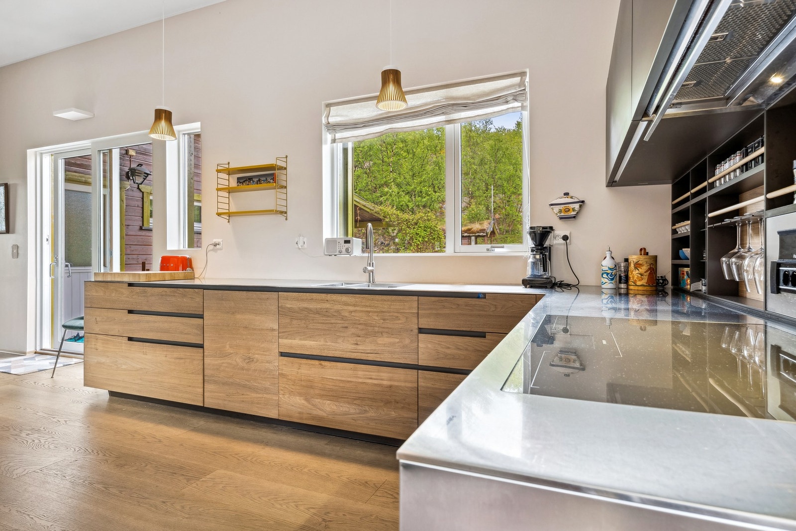 Kjøkkenet har praktiske løsninger og benkeplate av stål. Det er og utgang til uteplassene, noe som gjør det enkelt å bringe med seg måltidet ut når været tillater det Galleribilde