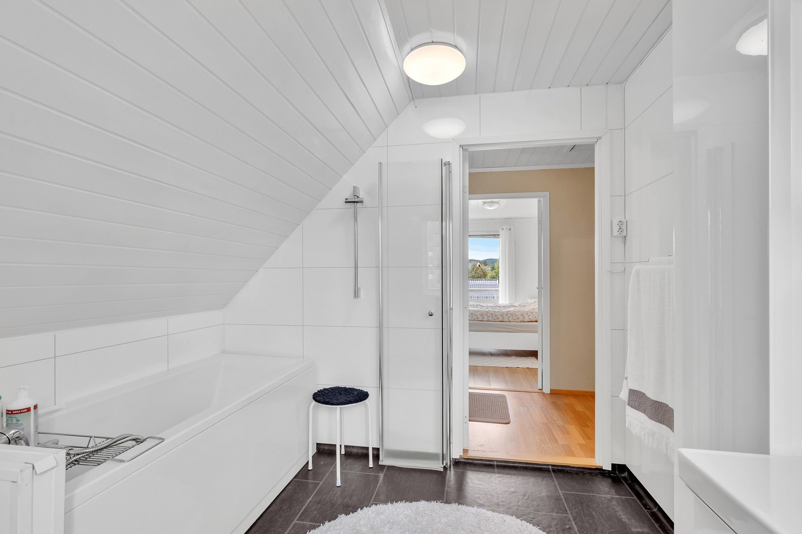 Badet er utstyrt med badekar og en åpen dusjplass med 1 stk. foldedør. Galleribilde