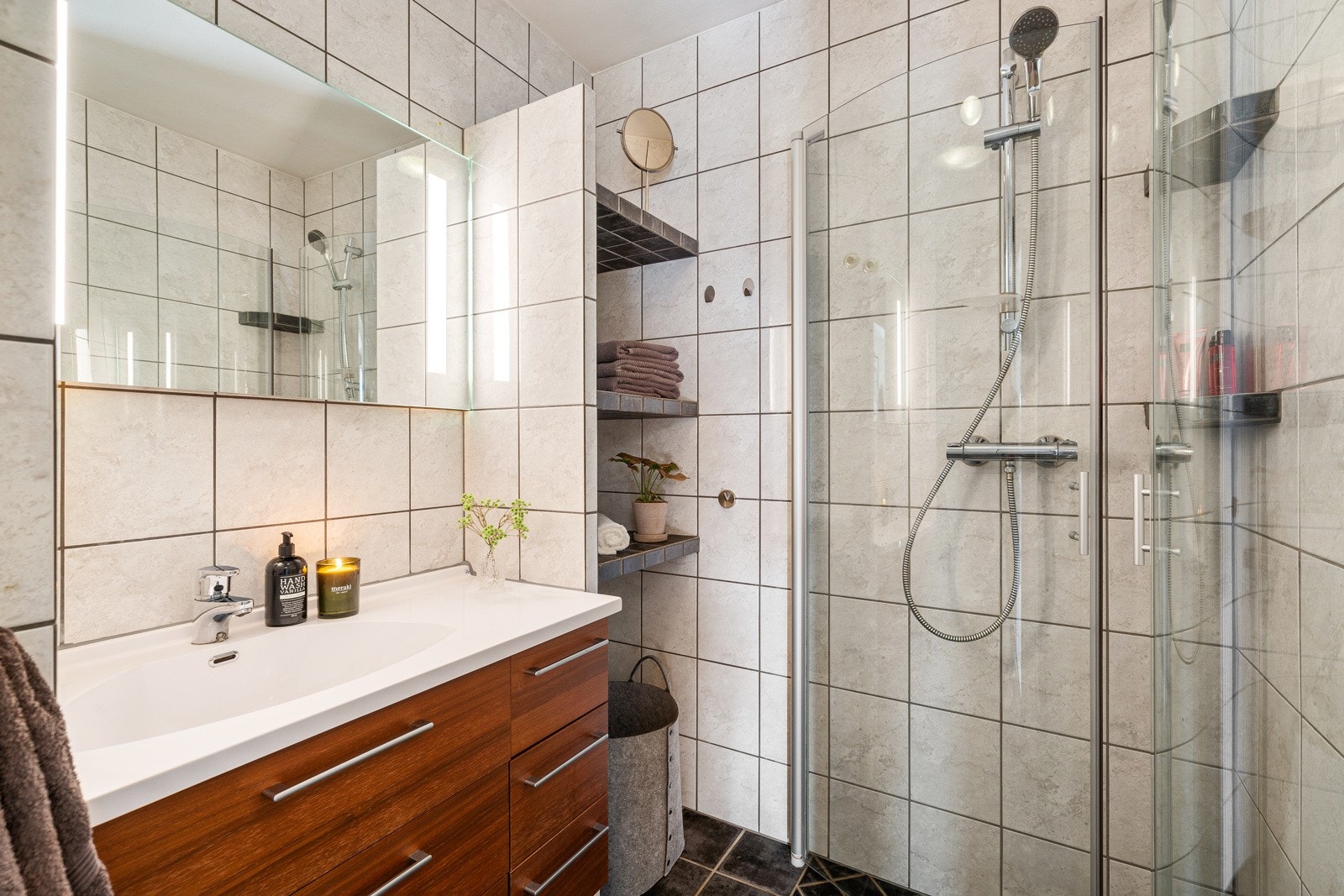 Flott bad med dusjhjørne av glass og servantinnredning med speil. Galleribilde