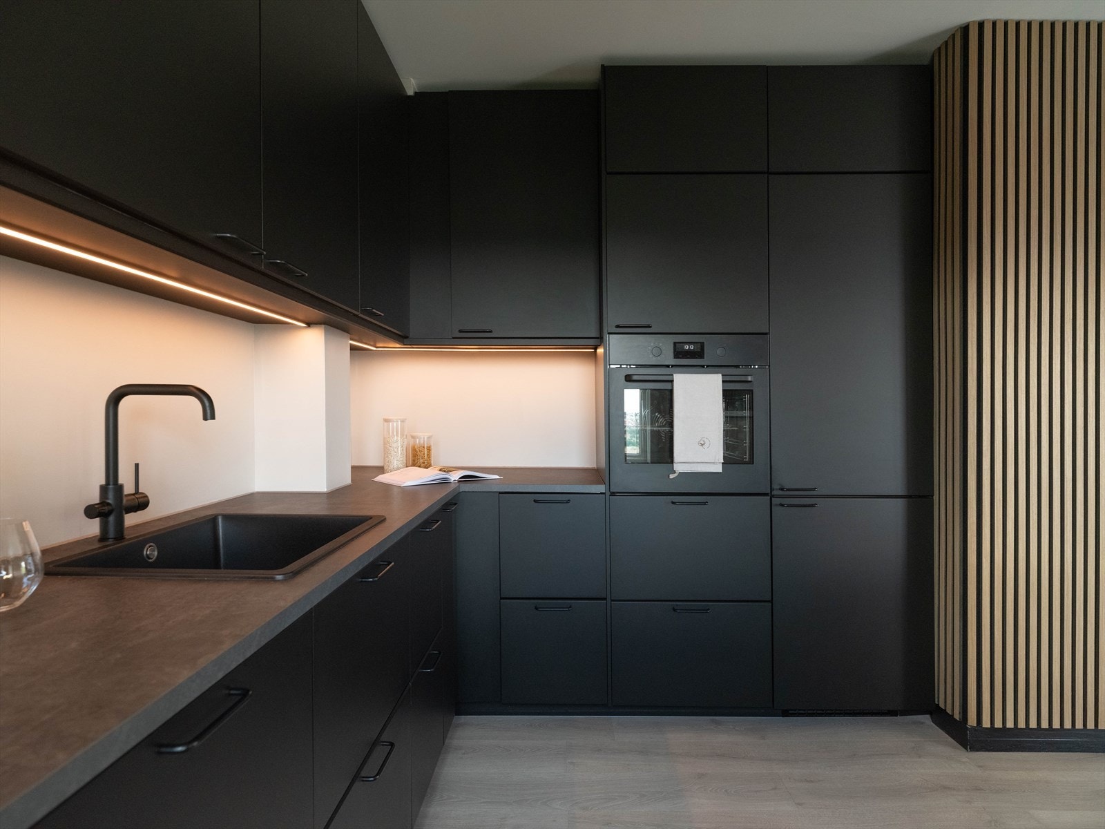 Stilrent kjøkken med sorte fronter og integrerte hvitevarer. Galleribilde