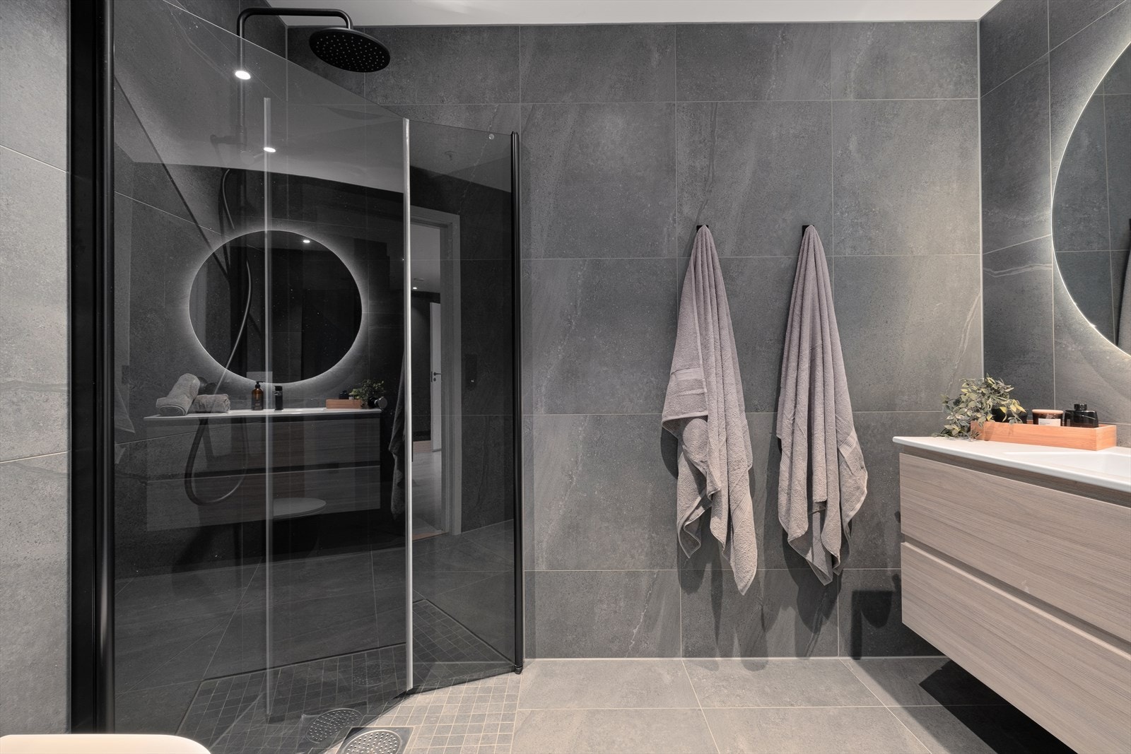 Badet er innredet med dusjhjørne, vegghengt toalett, servant med møblement og speil med belysning over. Galleribilde