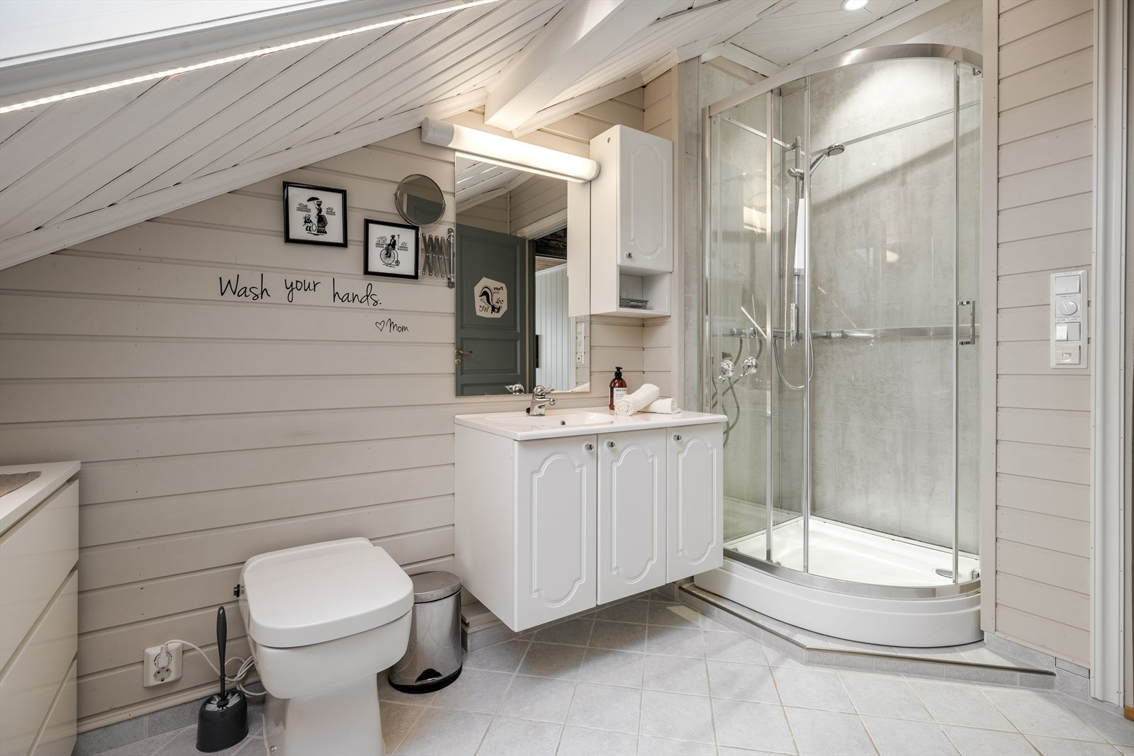 Her er det en romslig innredning med nedfelt servant samt overskap og speil på vegg med overlys. Badet er også innredet med kverntoalett og dusjkabinett. Galleribilde