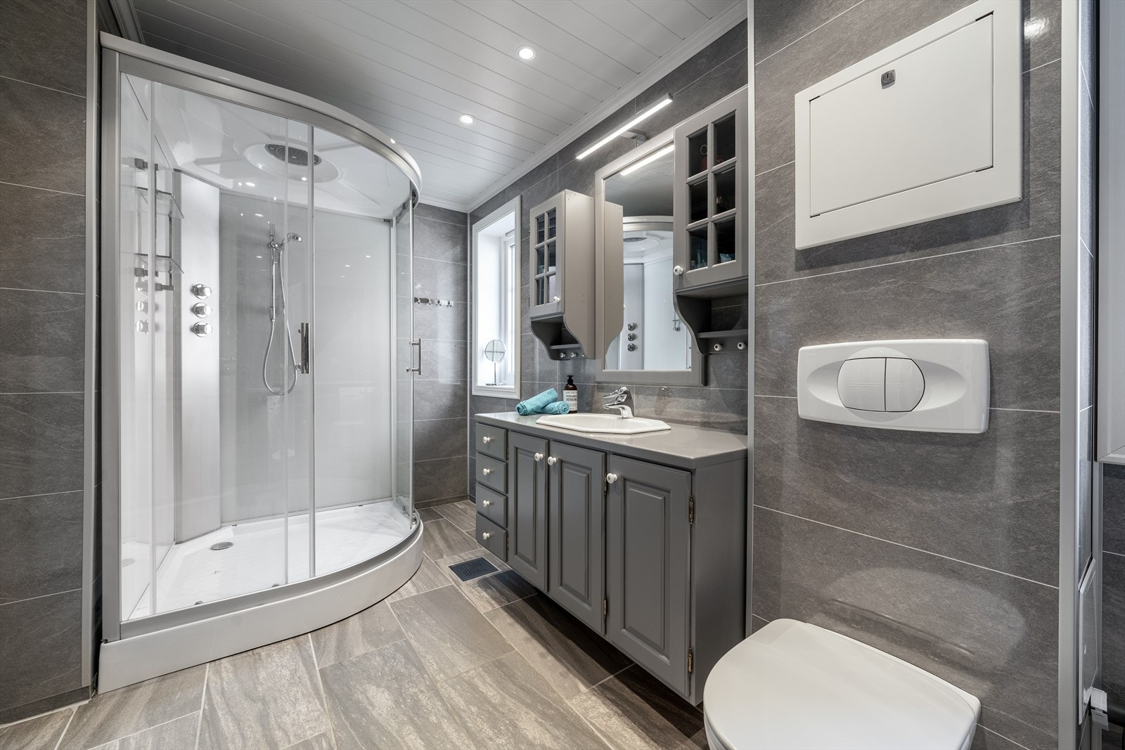 Badet er overflatemodernisert med ny varmekabel og flis på gulv og baderomsplater på vegg 2021. Her er godt med oppbevaringsplass i innredning med nedfelt servant samt i overskap og høyskap. Speil på vegg med overlys. Galleribilde