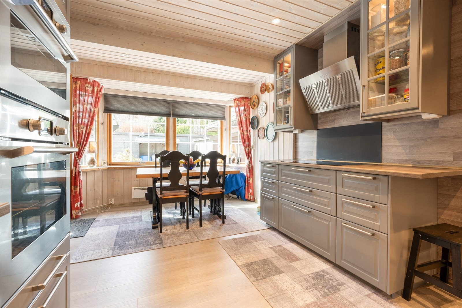 Over kokesonen er det en stilig, skråstilt ventilator med avtrekk ut, og under oppvaskmaskin er det montert vannstopper med føler.
Kjøkkenet har en romslig spiseplass med store vindusflater ut mot inngangspartiet og terrassen, og her er det også dør ut. Galleribilde