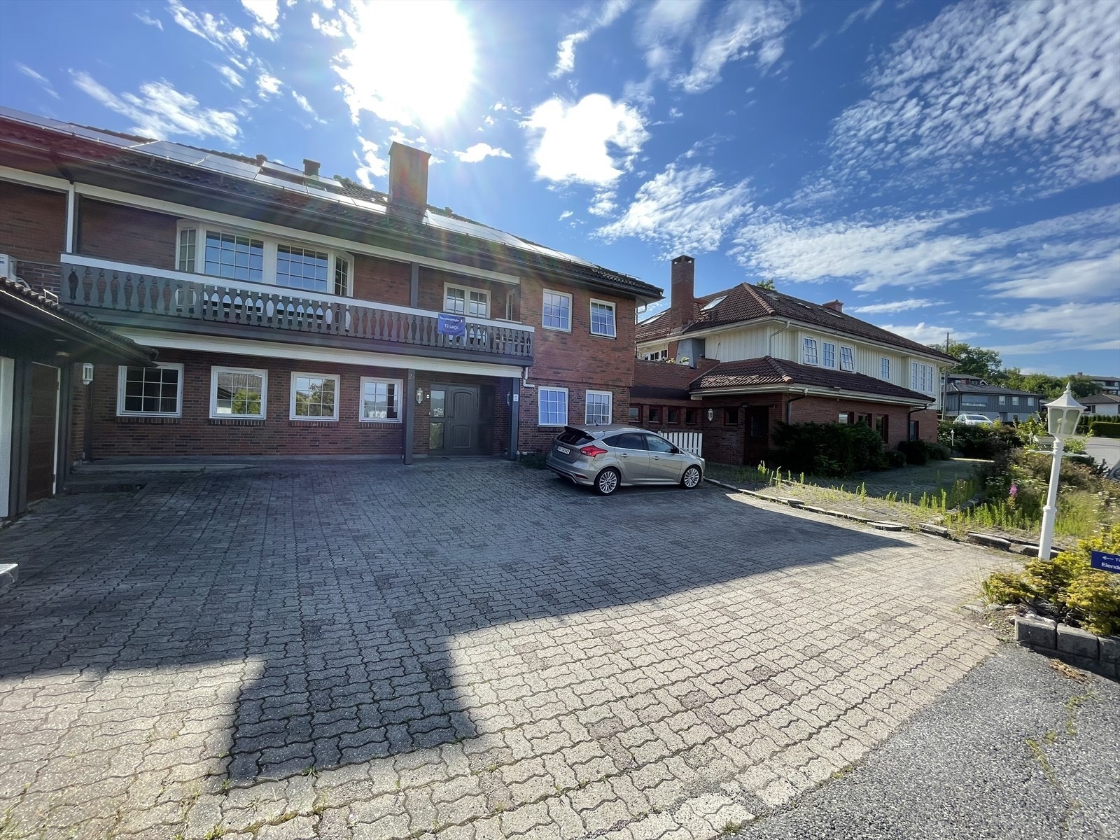 Sokkeletasjen med 3 hybler og adresse Strømdallia 2A har egen innkjørsel. Her er det en meget romslig gårdsplass med belegningsstein hvor det er flere biloppstillingsplasser. Galleribilde