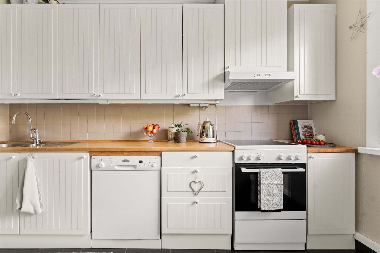 Innredningen har profilerte fronter, samt laminat benkeplate med nedfelt kum i rustfritt stål. Det er fliser på vegg over benkeplaten, i tillegg til belysning under overskapene. Galleribilde