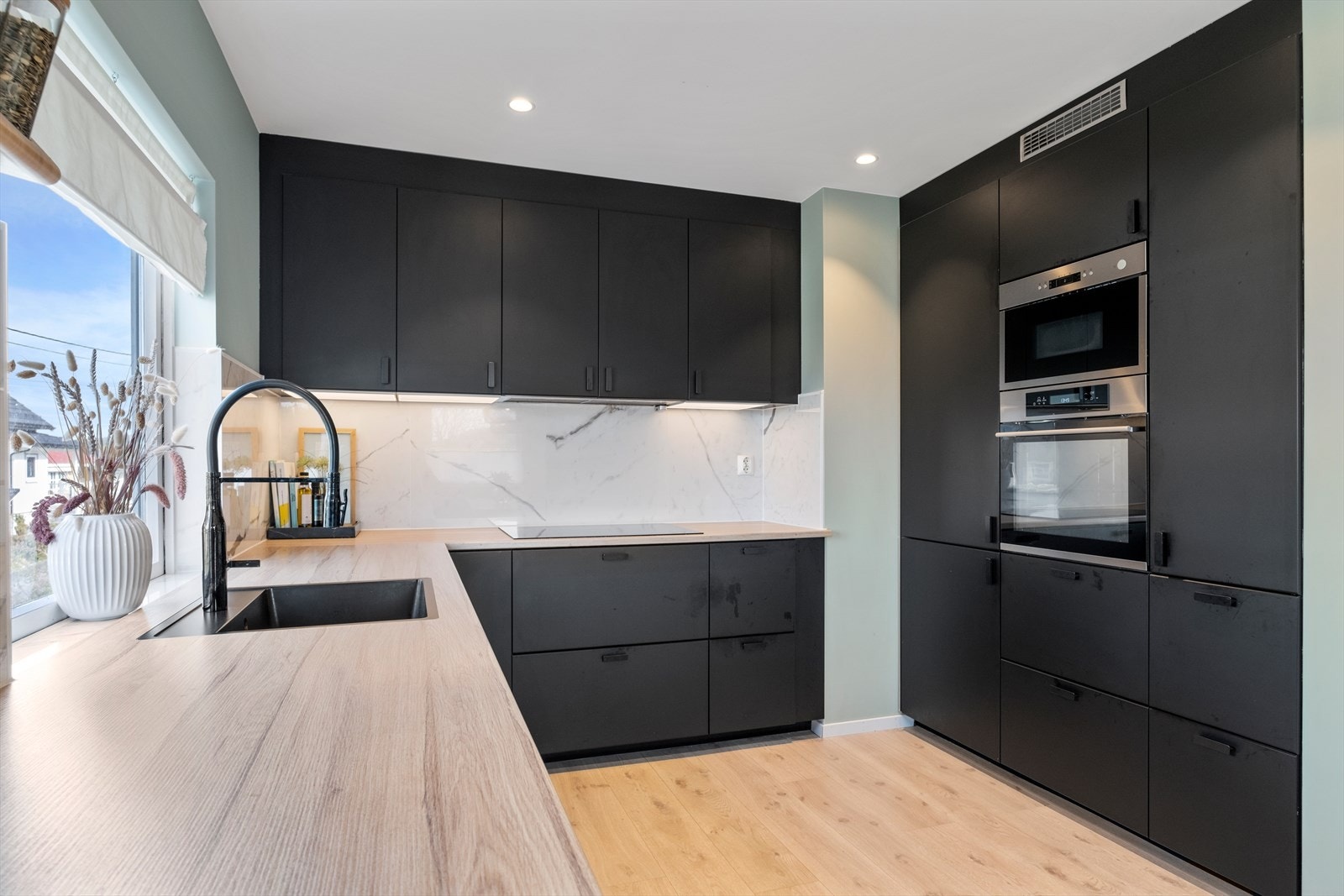 Laminat benkeplate med nedfelt oppvaskkum. Det er installert waterguard i benk. Det er kjøkkenventilator med avtrekk ut. Galleribilde